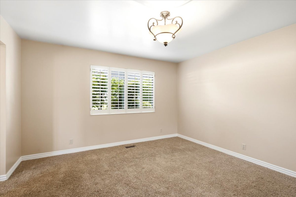 Spacious interior room with neutral-toned walls, plush carpet flooring, and white baseboards