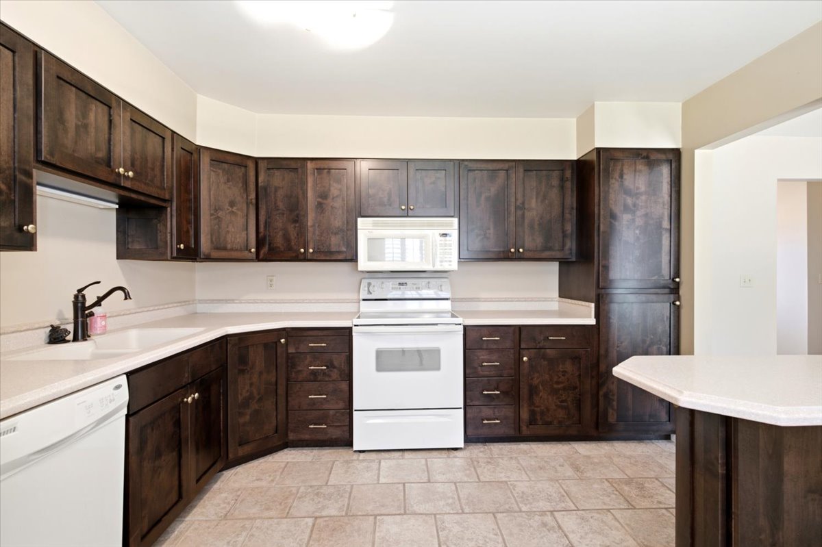 Kitchen featuring dark wood-finish cabinetry, light countertops, and tile flooring
