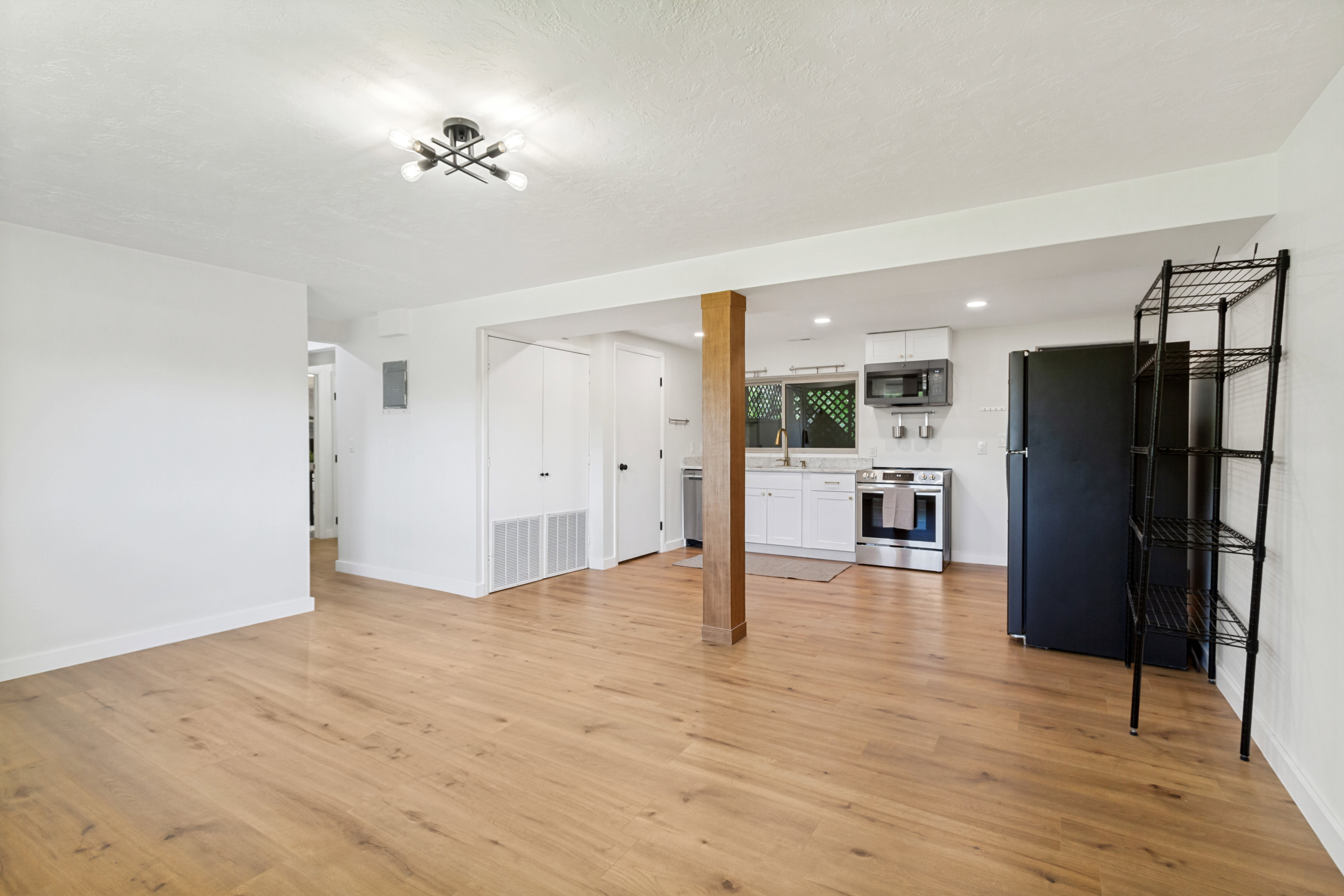 Open-concept living space featuring wood-finish flooring and a contemporary light fixture