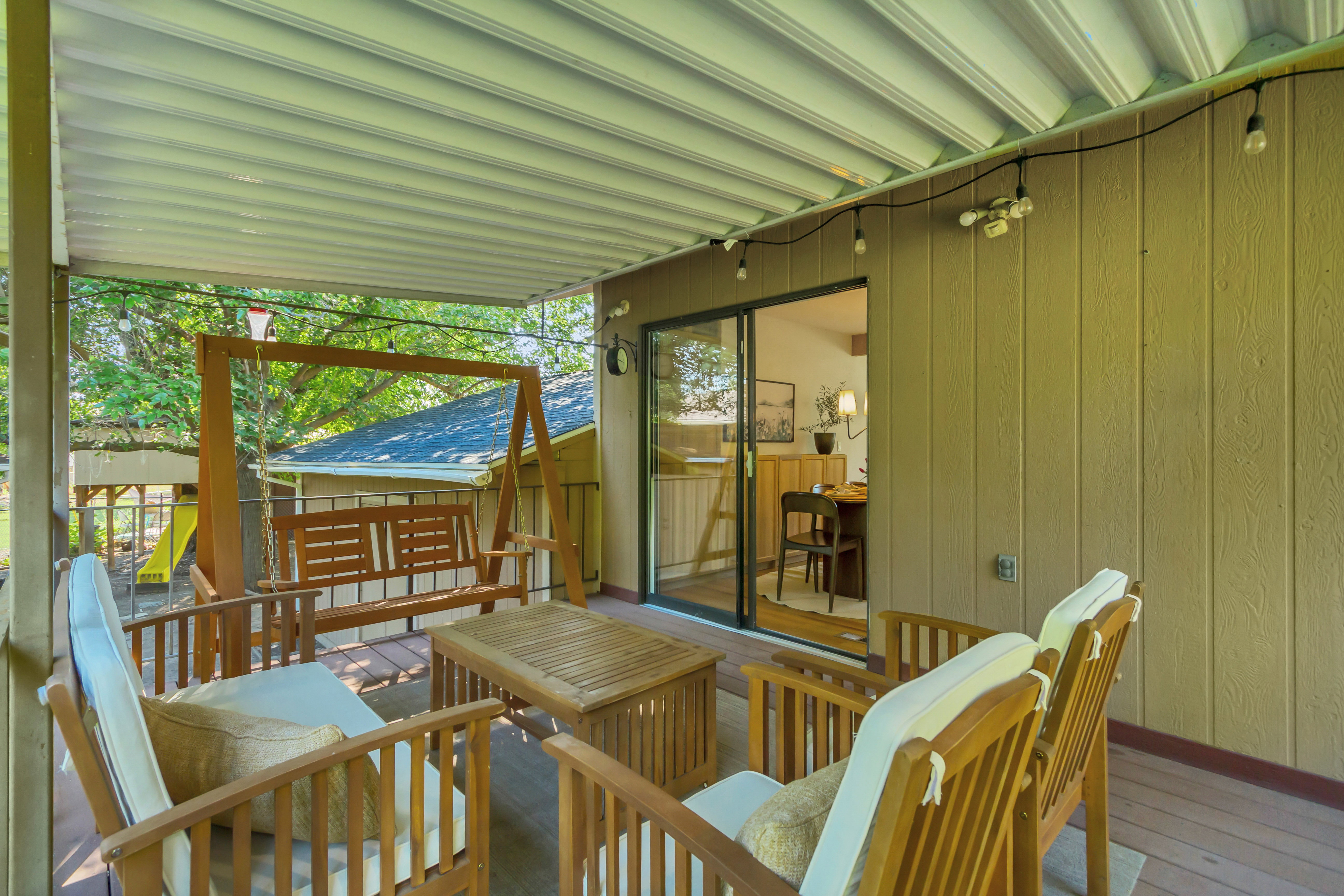 Covered outdoor deck featuring a wooden swing, recessed lighting, string lighting, and direct access to the interior via a sliding glass door