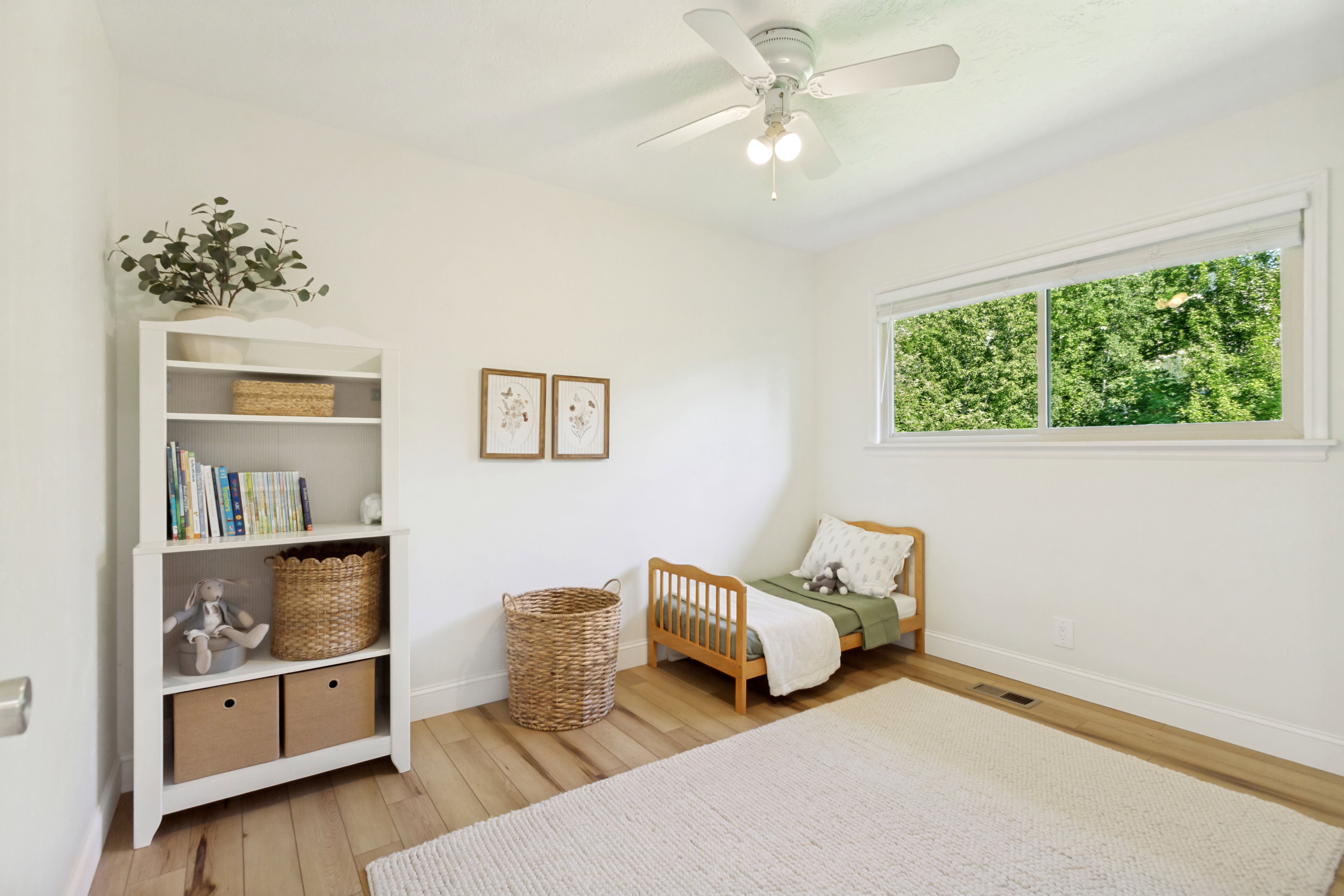 Bright interior space featuring a ceiling fan with light fixture, wood-finish flooring, white baseboards, and a large horizontal window
