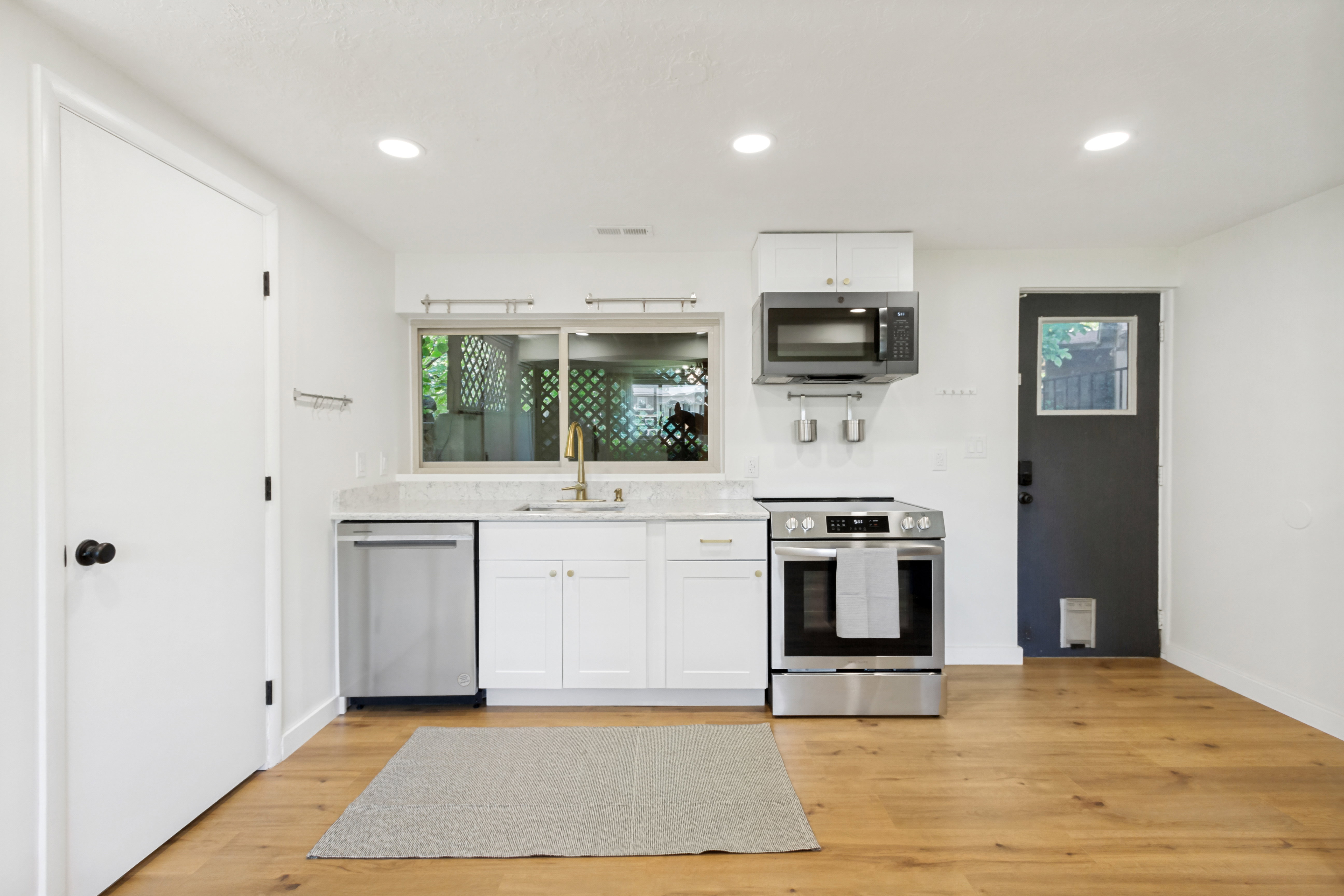 Bright kitchen area featuring wood-finish flooring, recessed lighting, and white cabinetry