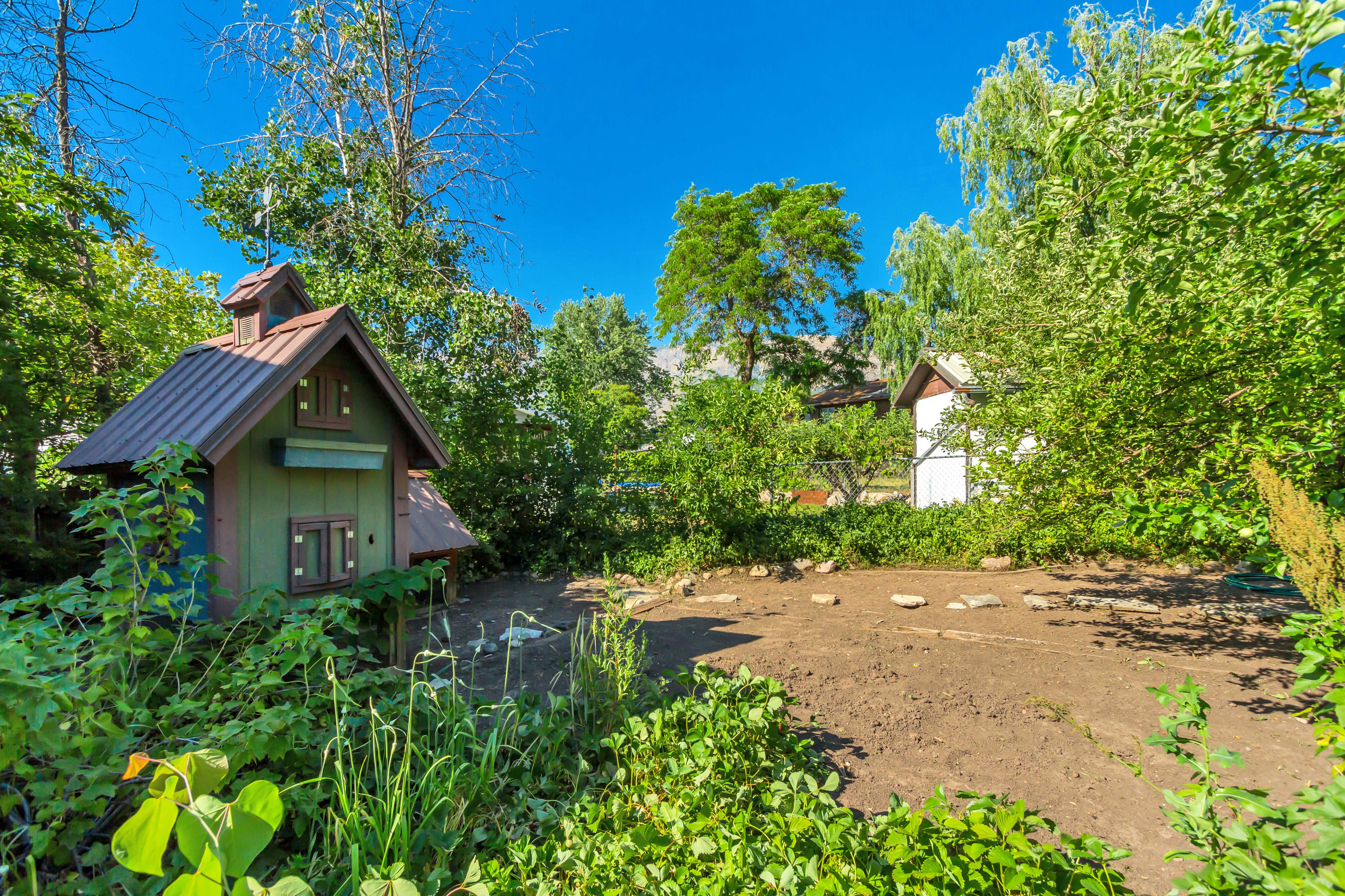 Garden structure featuring a brown metal roof, green siding, and decorative windows