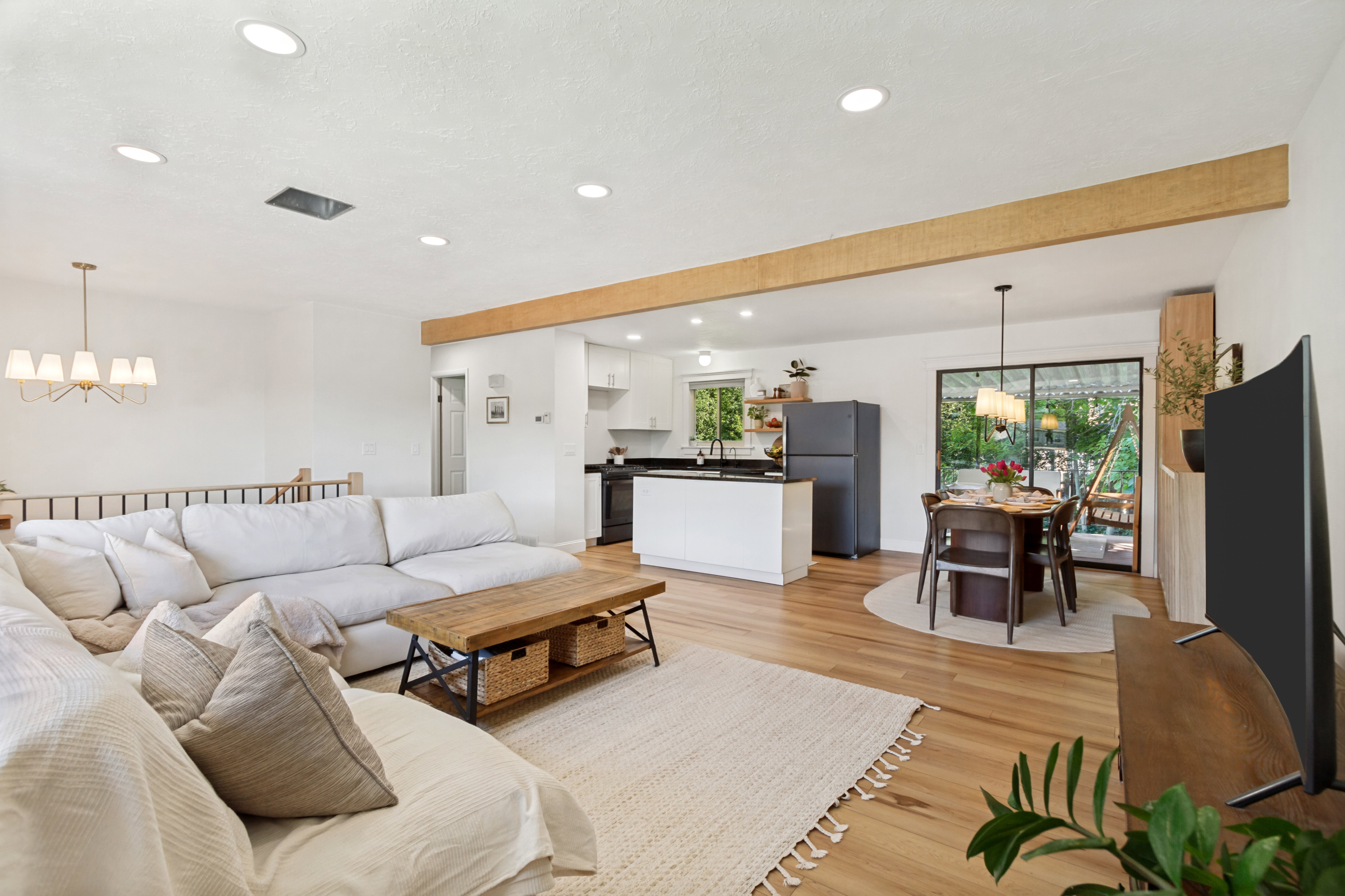 Open concept living space featuring recessed lighting, a decorative wood beam, wood-finish flooring, a kitchen island with seating, and sliding glass doors to the exterior