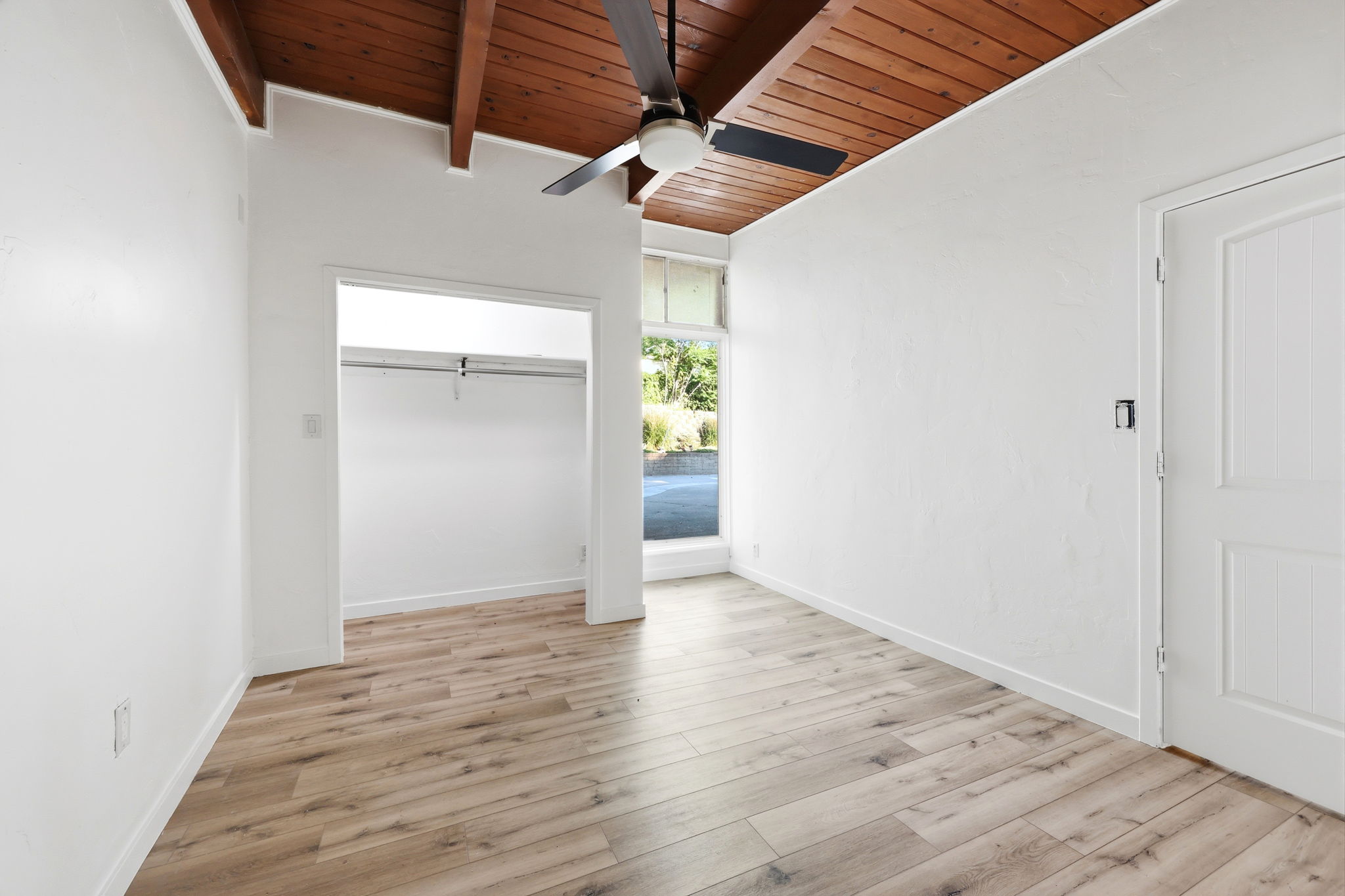 Room featuring exposed wood beam ceiling, wood-finish flooring, and white walls