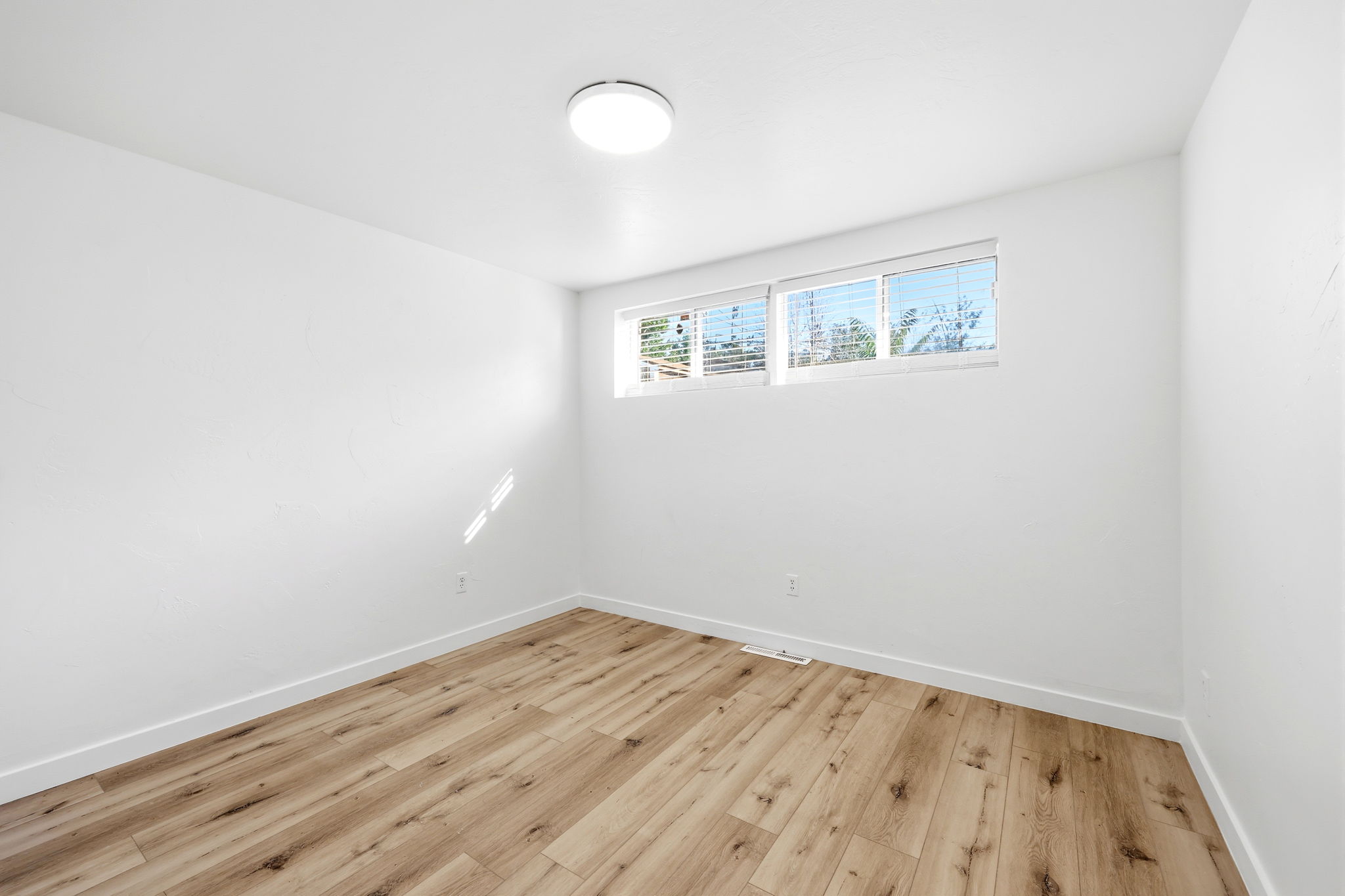 Bright interior space featuring wood-finish flooring, white walls, and multiple windows
