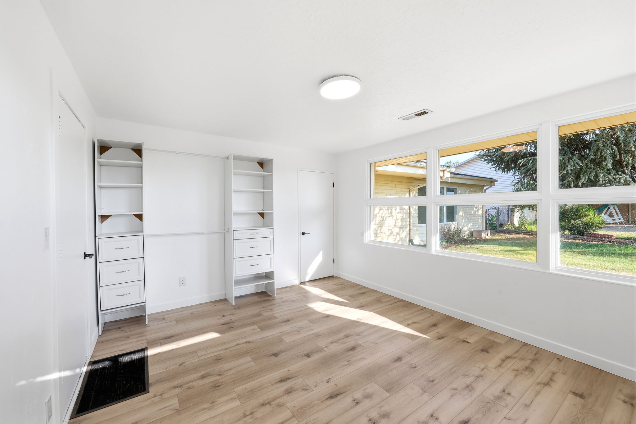 Room featuring wood-finish flooring, white walls, and multiple windows