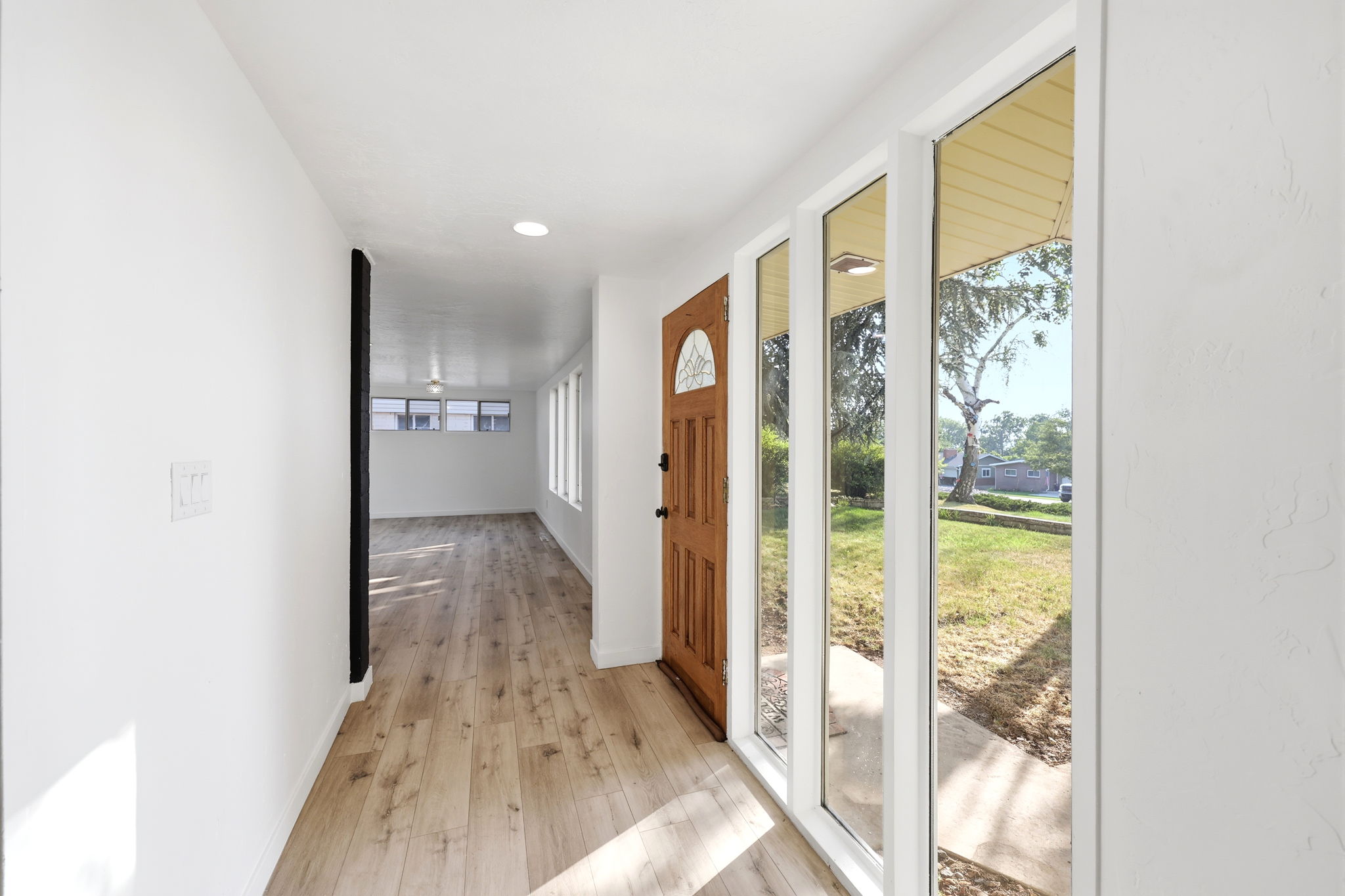 Entryway featuring a wood-panel door with an arched glass insert, alongside a series of vertical windows
