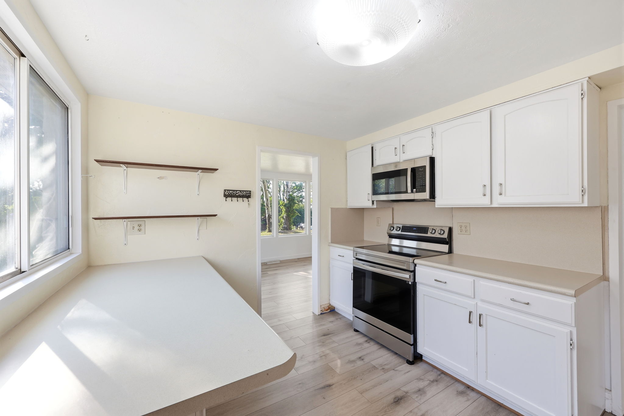 Updated kitchen featuring white cabinetry, light countertops, and stainless steel appliances including a range and microwave