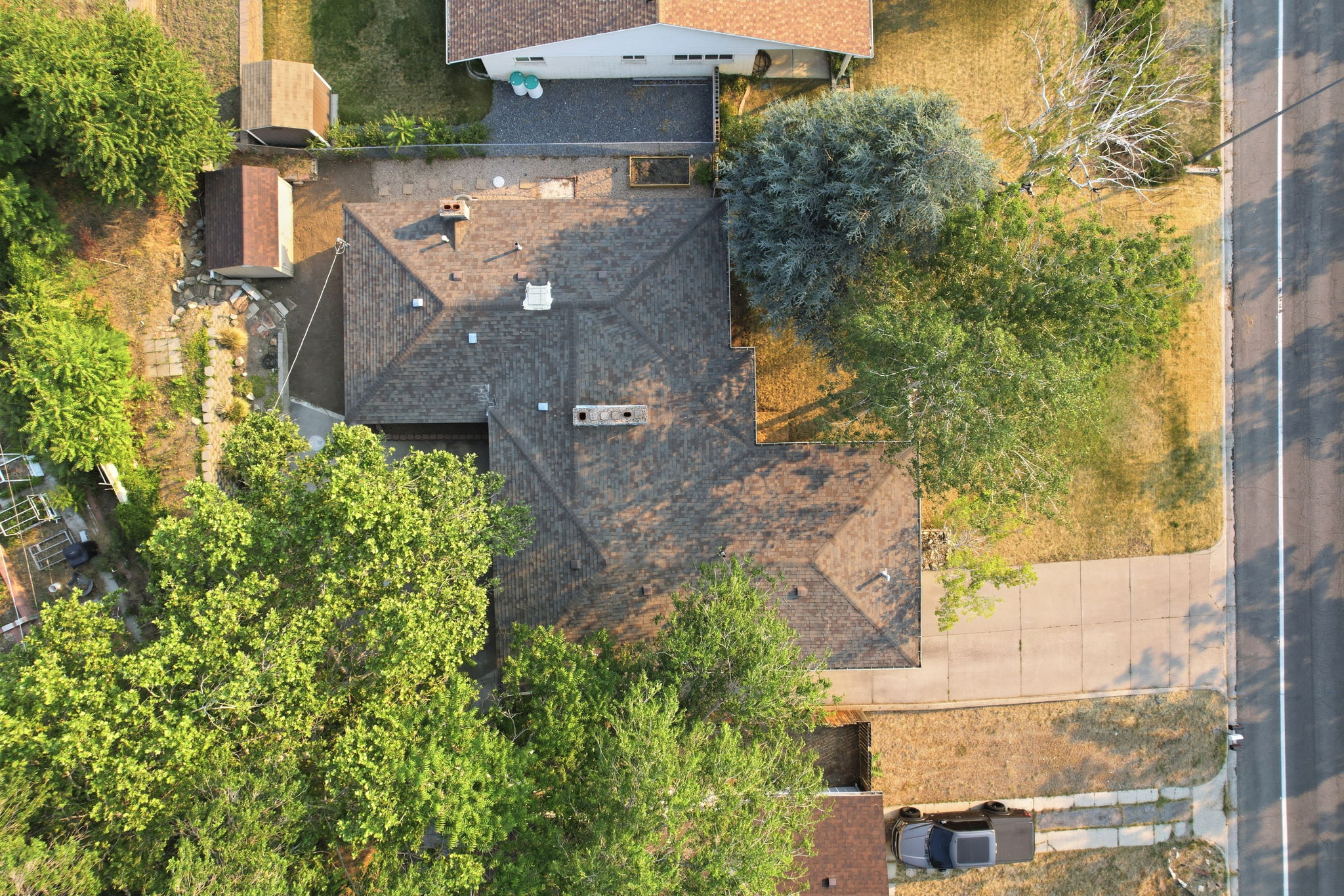 Residential property featuring a shingle roof and multiple mature trees