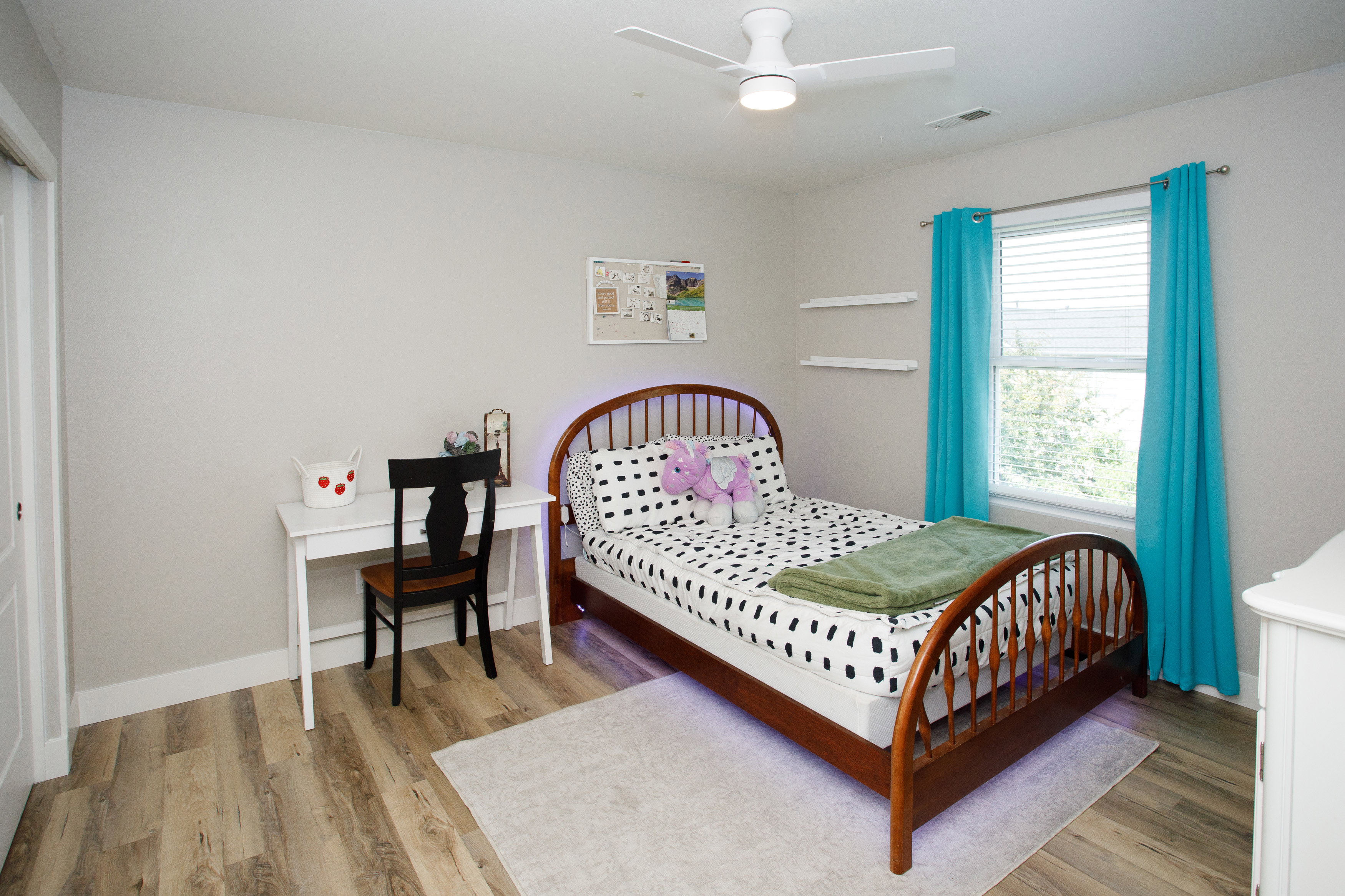 Bright room featuring wood-finish flooring, a white ceiling fan with integrated lighting, and a window with blinds