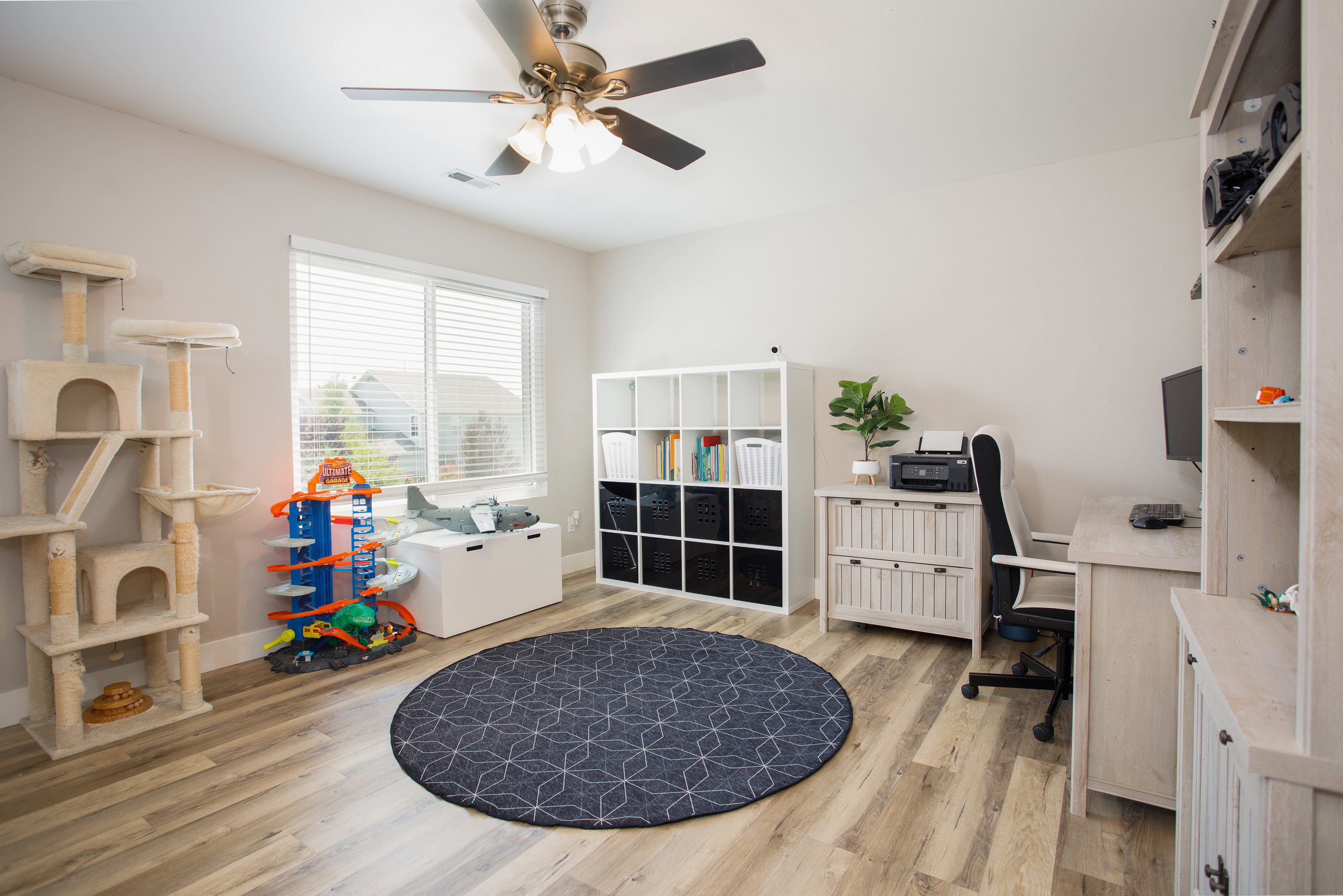Bright room featuring wood-finish flooring and a ceiling fan with integrated lighting