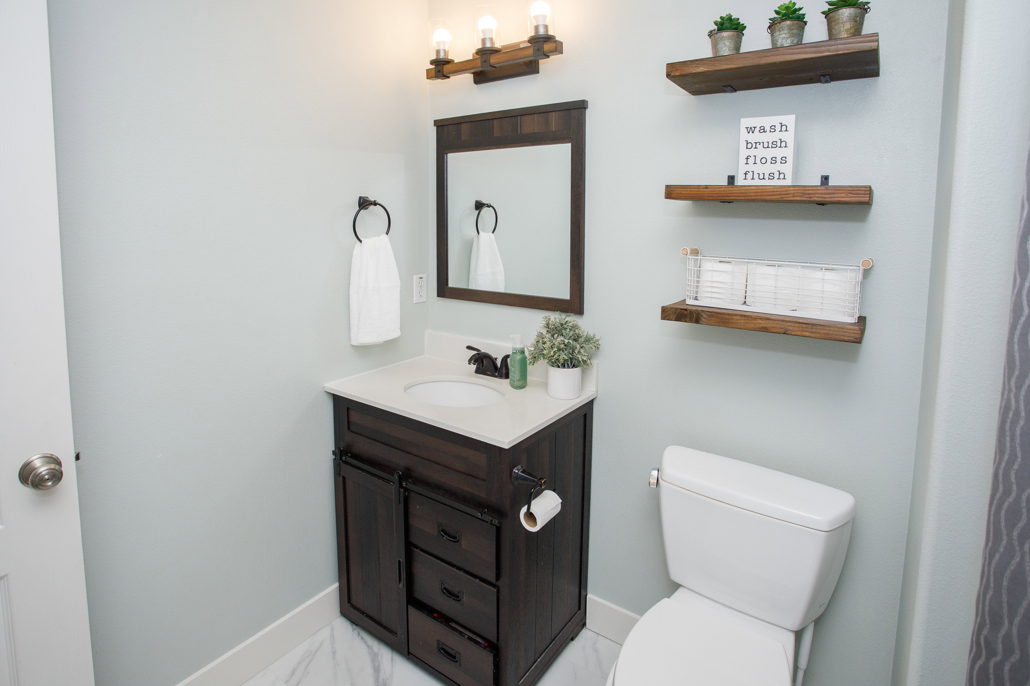 Bathroom featuring a dark wood-finish vanity with an integrated sink, a complementing dark wood-frame mirror, and a three-light fixture