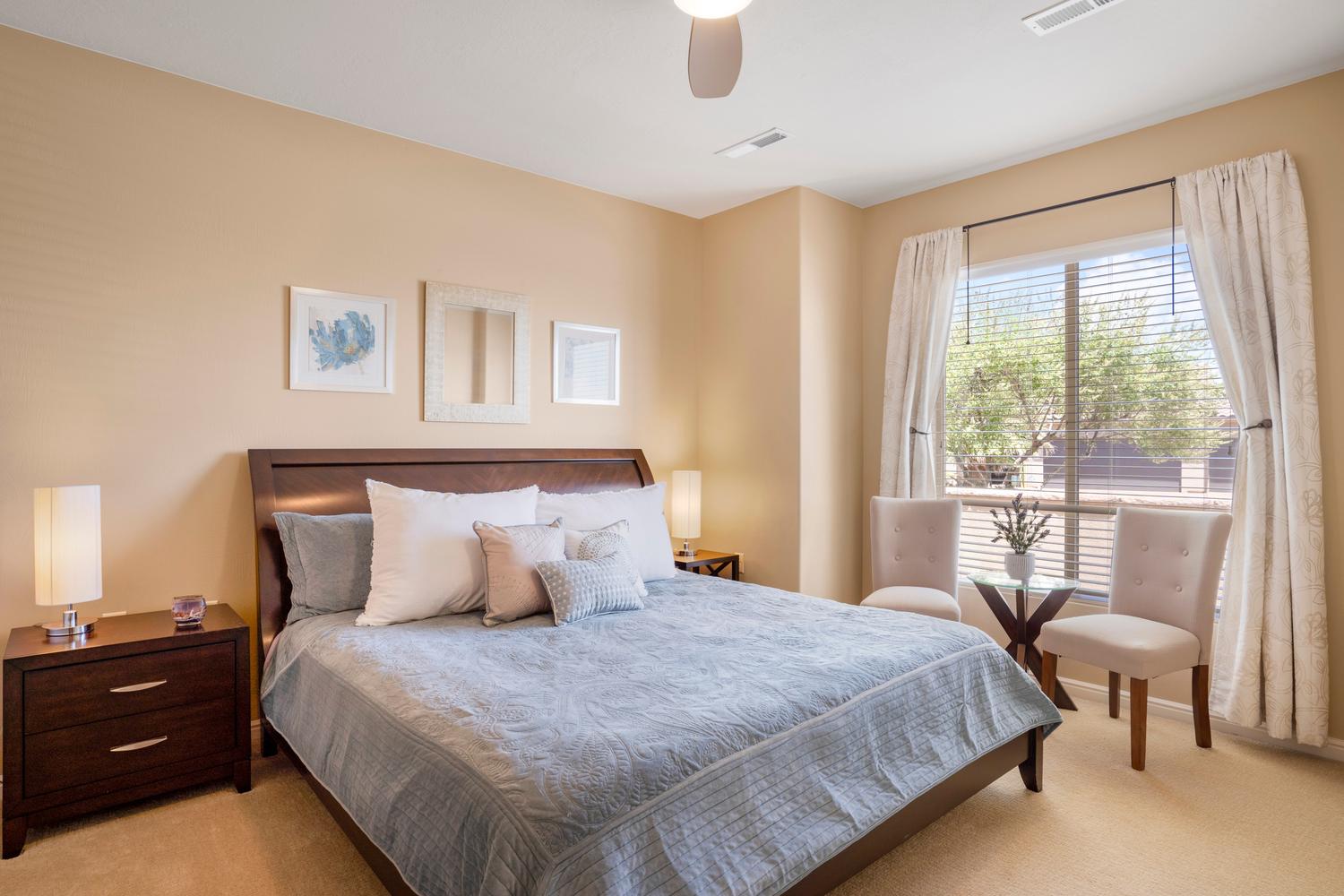 Carpeted bedroom featuring a ceiling fan, a large window with blinds and drapes, and a built-in wall niche