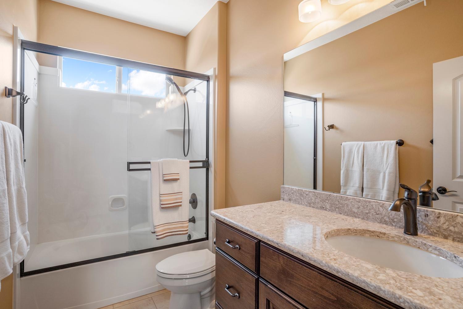 Bathroom featuring a single vanity with a light-colored countertop, an undermount sink, and a dark wood-finish cabinet