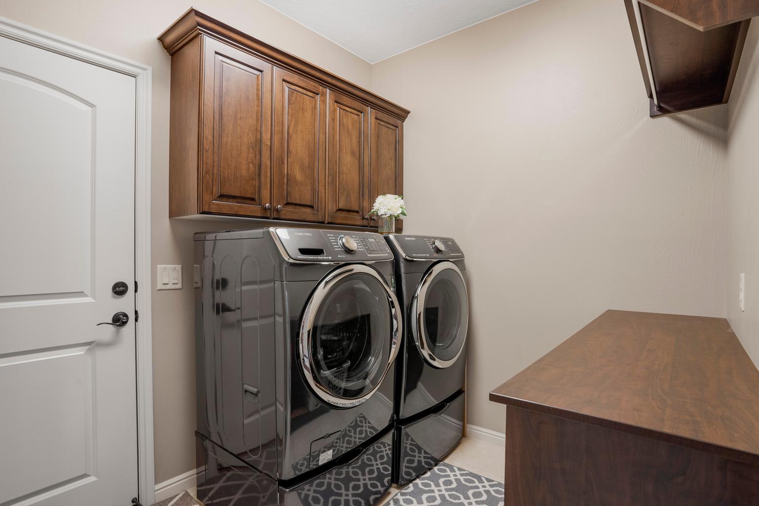 Laundry area featuring dark wood-finish cabinetry, a white panel door with dark hardware, and a built-in wood-finish countertop