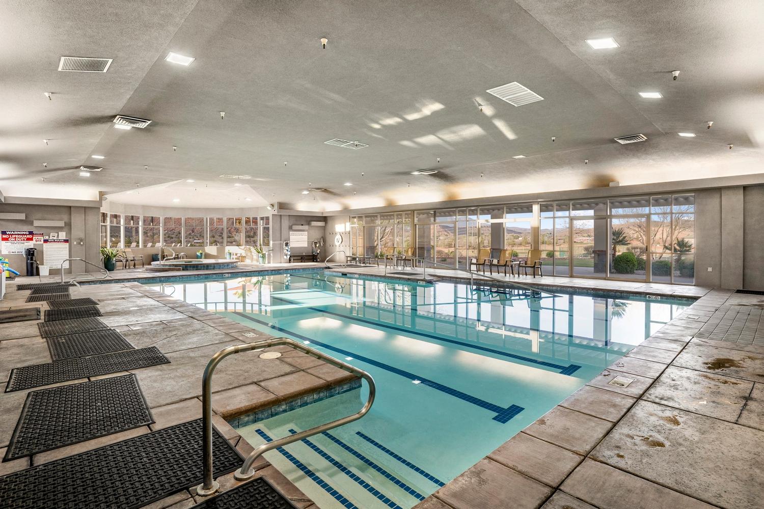 Indoor swimming pool featuring a tiled deck, integrated spa area, floor-to-ceiling windows, and recessed ceiling lighting