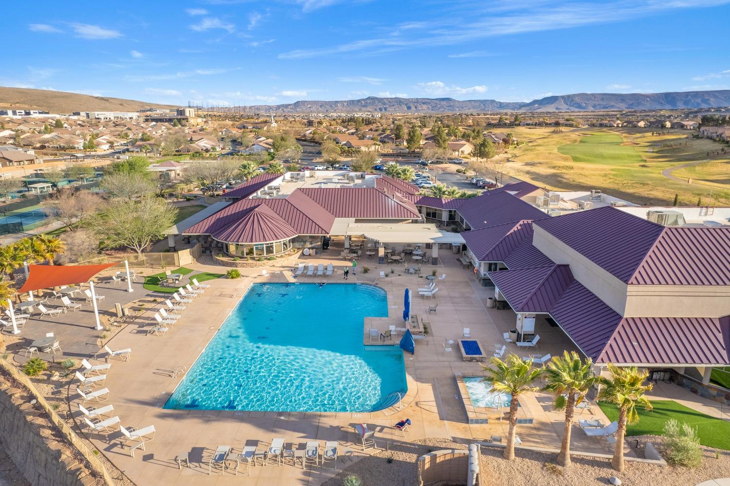 Expansive recreational complex featuring a large swimming pool, multiple lounging areas, and a spa