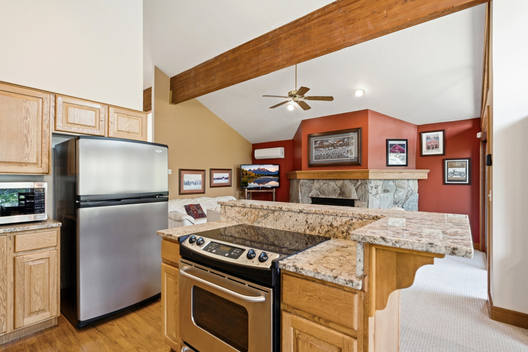Kitchen featuring granite countertops, wood-finish flooring, light wood cabinetry, and stainless steel appliances