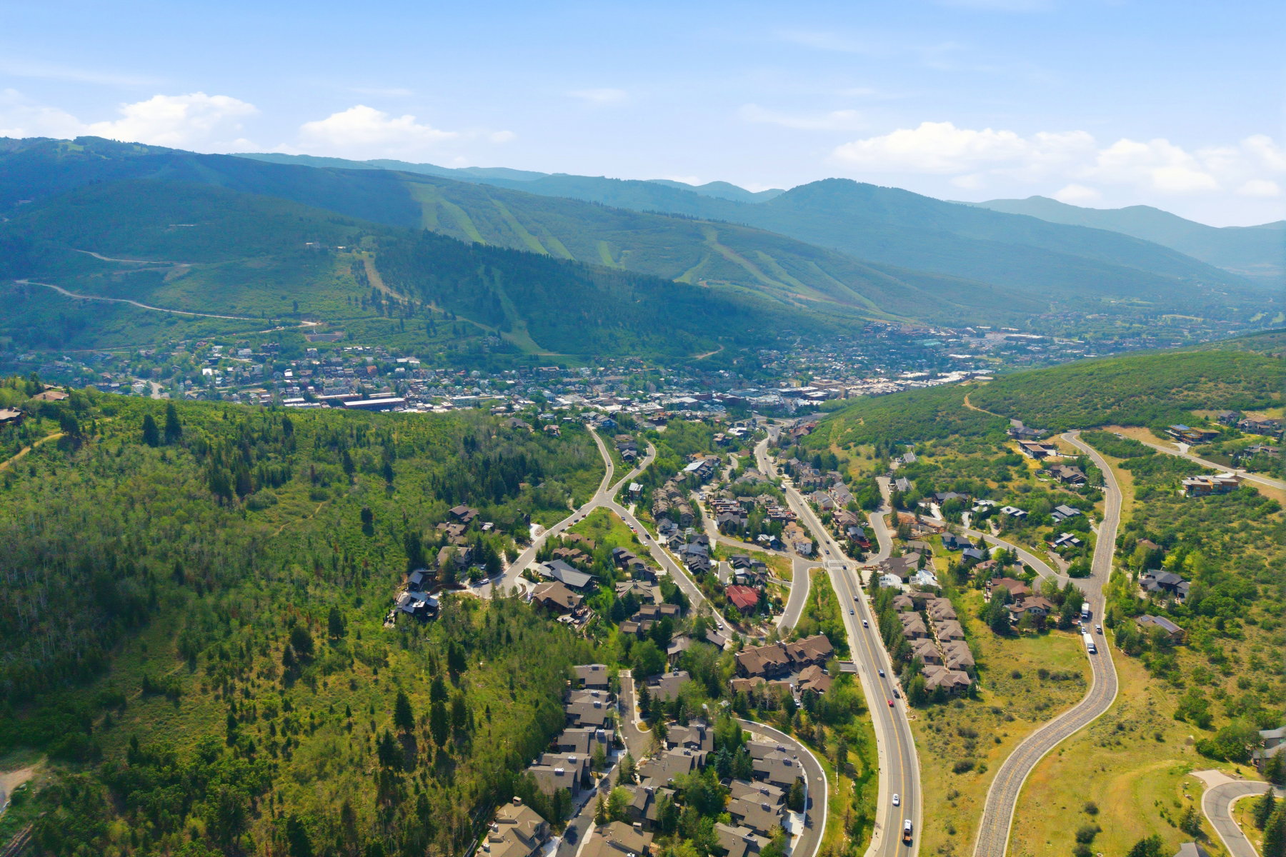 Expansive mountain valley setting featuring a distant town center and extensive green hillsides