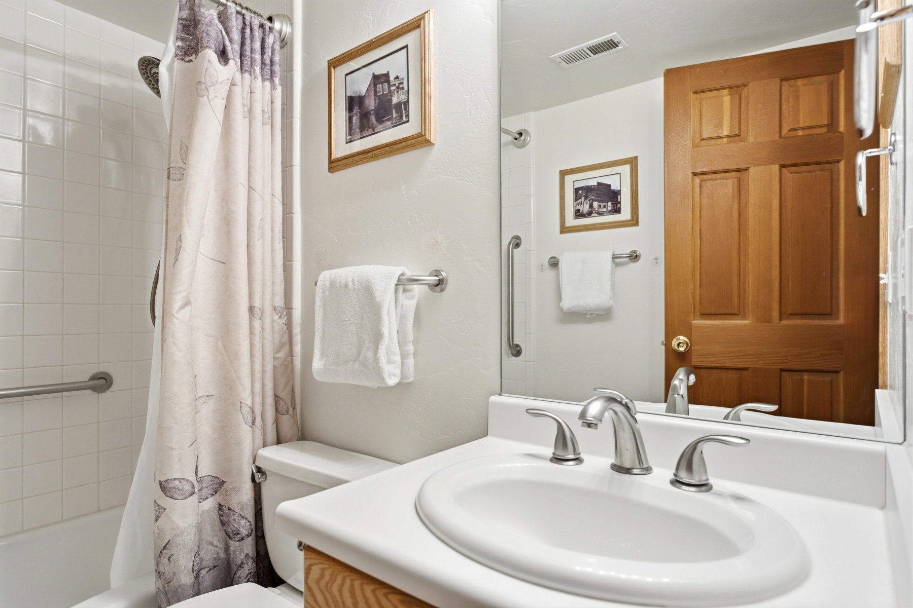 Bathroom featuring a white bathtub with subway tile surround, chrome fixtures, and a grab bar