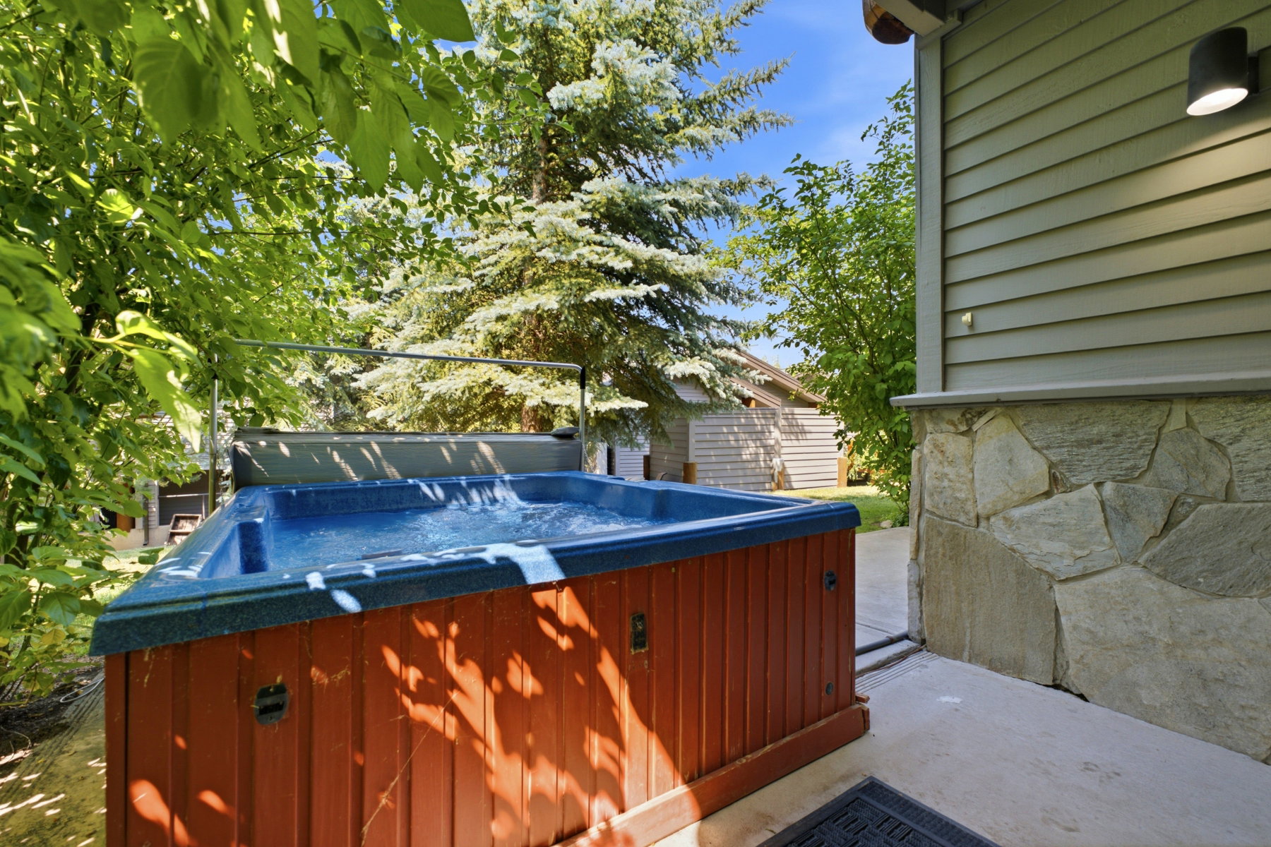 Outdoor spa tub with wood-finish siding, positioned on a concrete patio