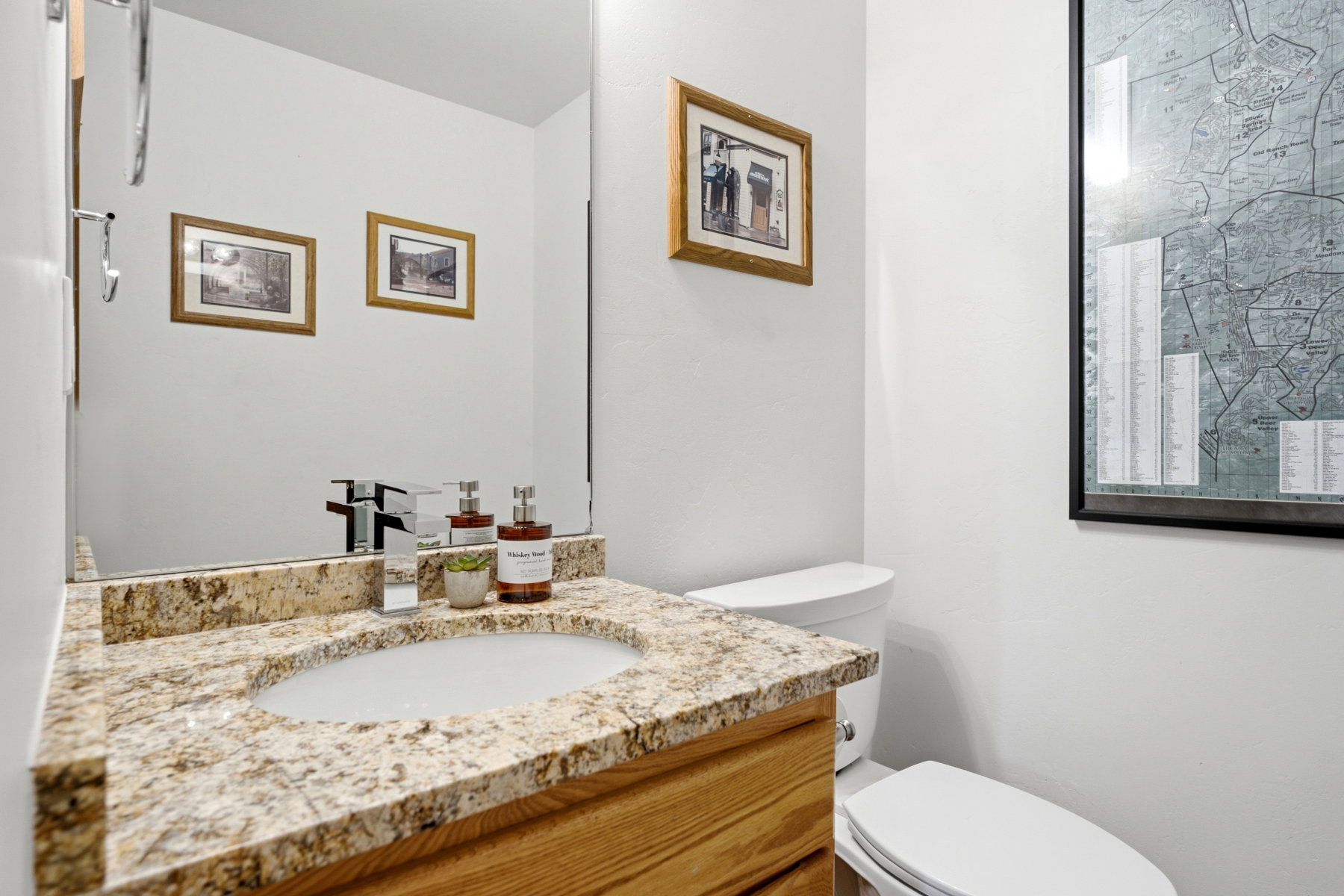 Vanity with an undermount sink and granite-finish countertop, wood-finish cabinetry, and chrome faucet
