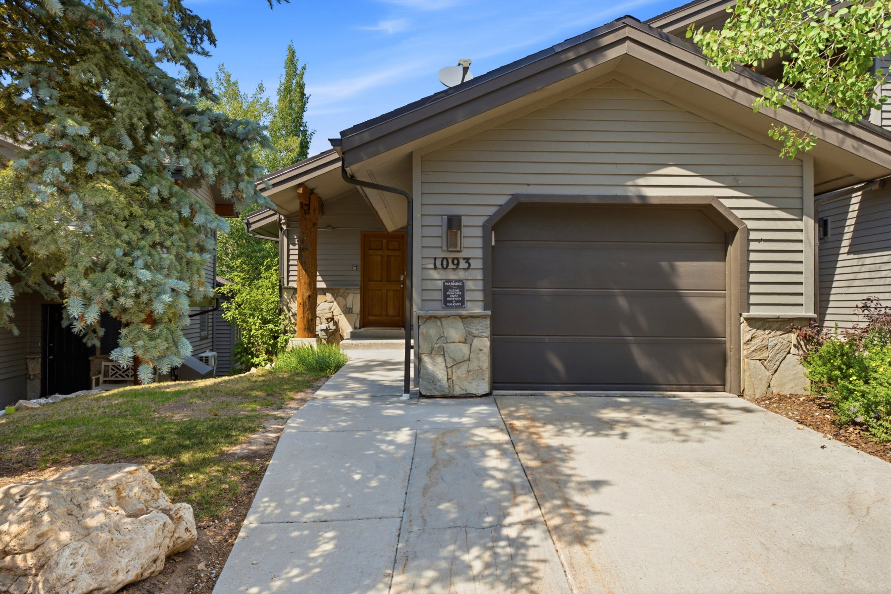 Exterior featuring horizontal siding, a stone facade, and a prominent garage door