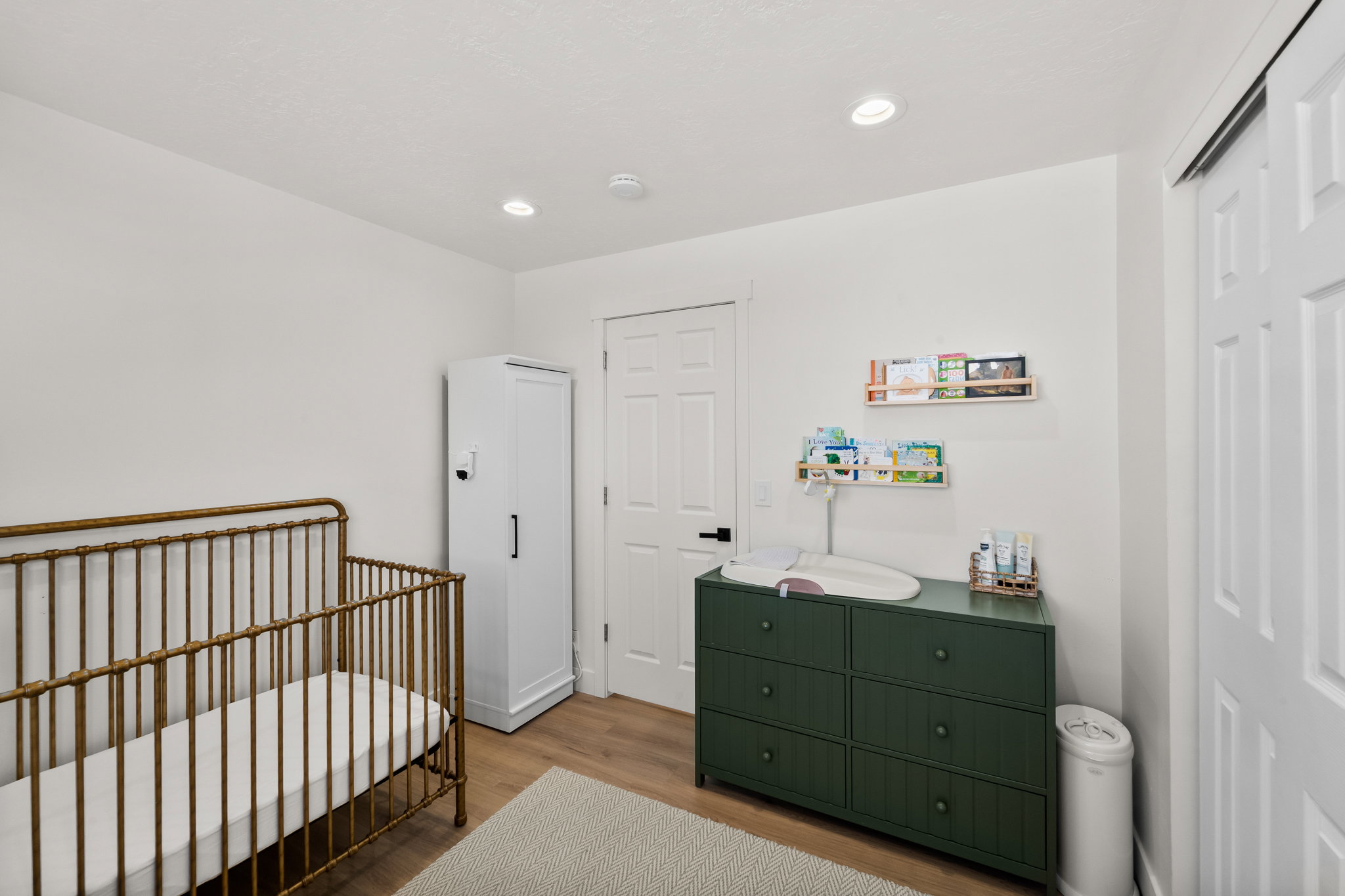 Bright room featuring recessed lighting, wood-finish flooring, white walls, and a white paneled door with black hardware