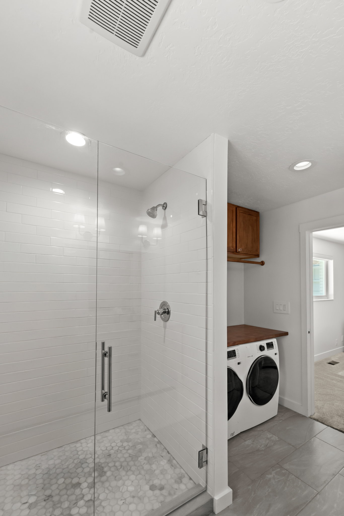 Glass-enclosed shower with white subway tile surround and hexagonal mosaic floor