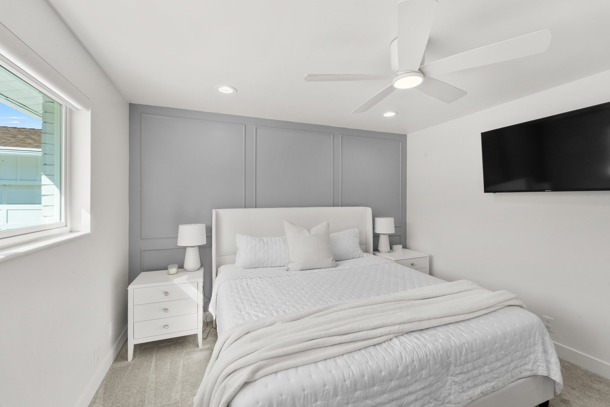 Bedroom featuring a decorative accent wall with panel molding, carpet flooring, a ceiling fan with integrated lighting, recessed lighting, and a wall-mounted television
