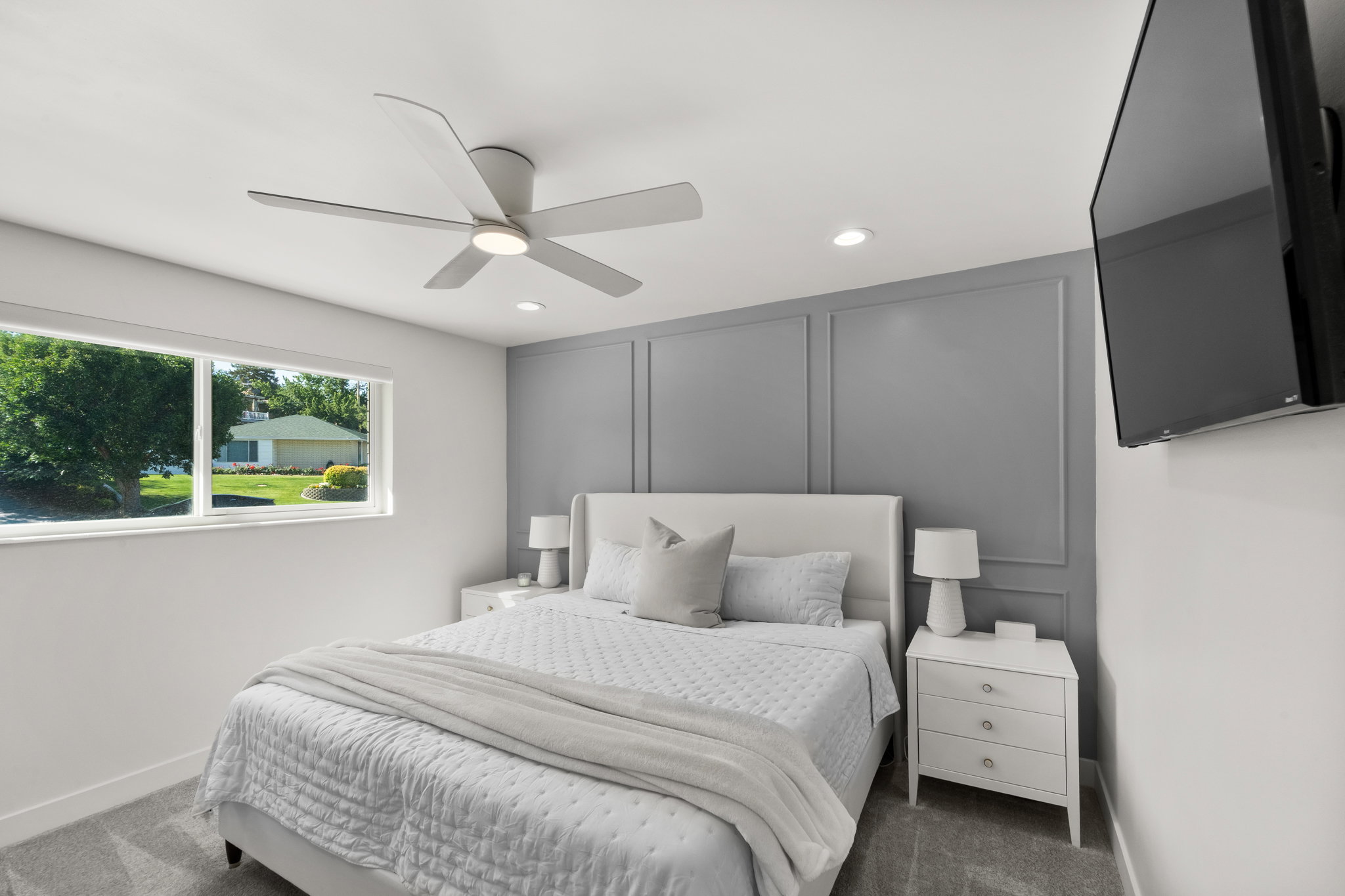 Recessed lighting and a modern ceiling fan illuminate this space, featuring a panel-accented wall