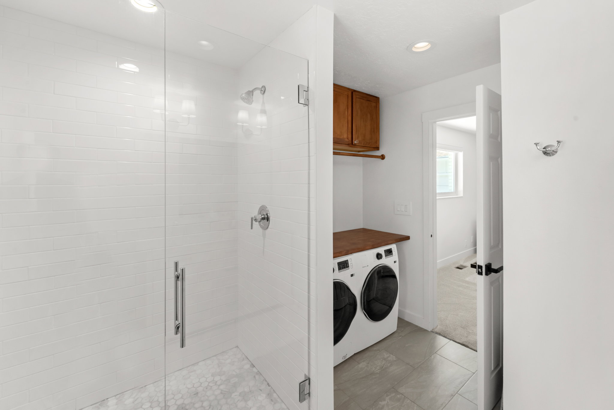 Walk-in shower with white subway tile surround and hexagonal tile flooring, featuring chrome fixtures