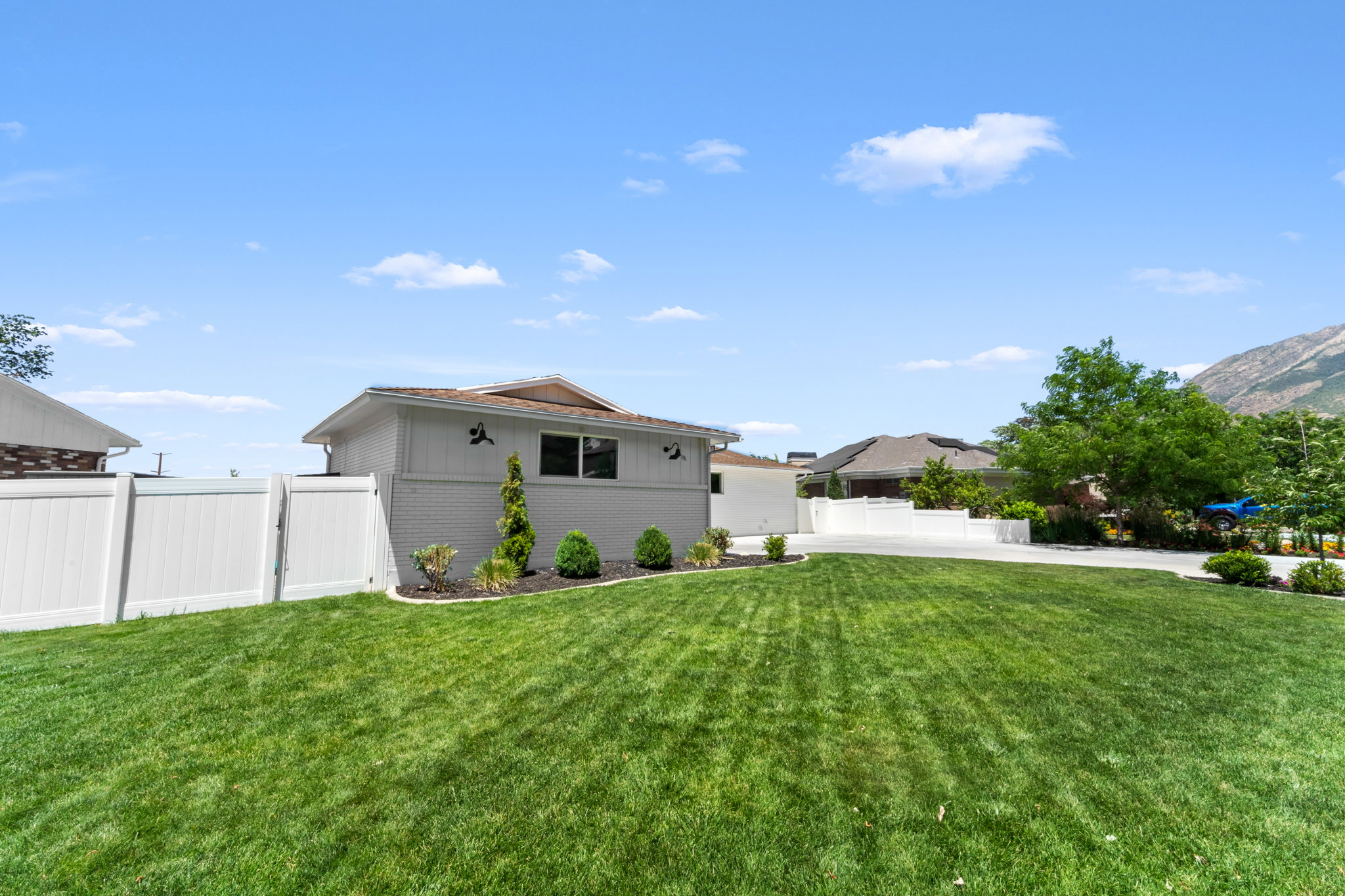 Expansive lawn area featuring well-maintained turf and a white vinyl privacy fence