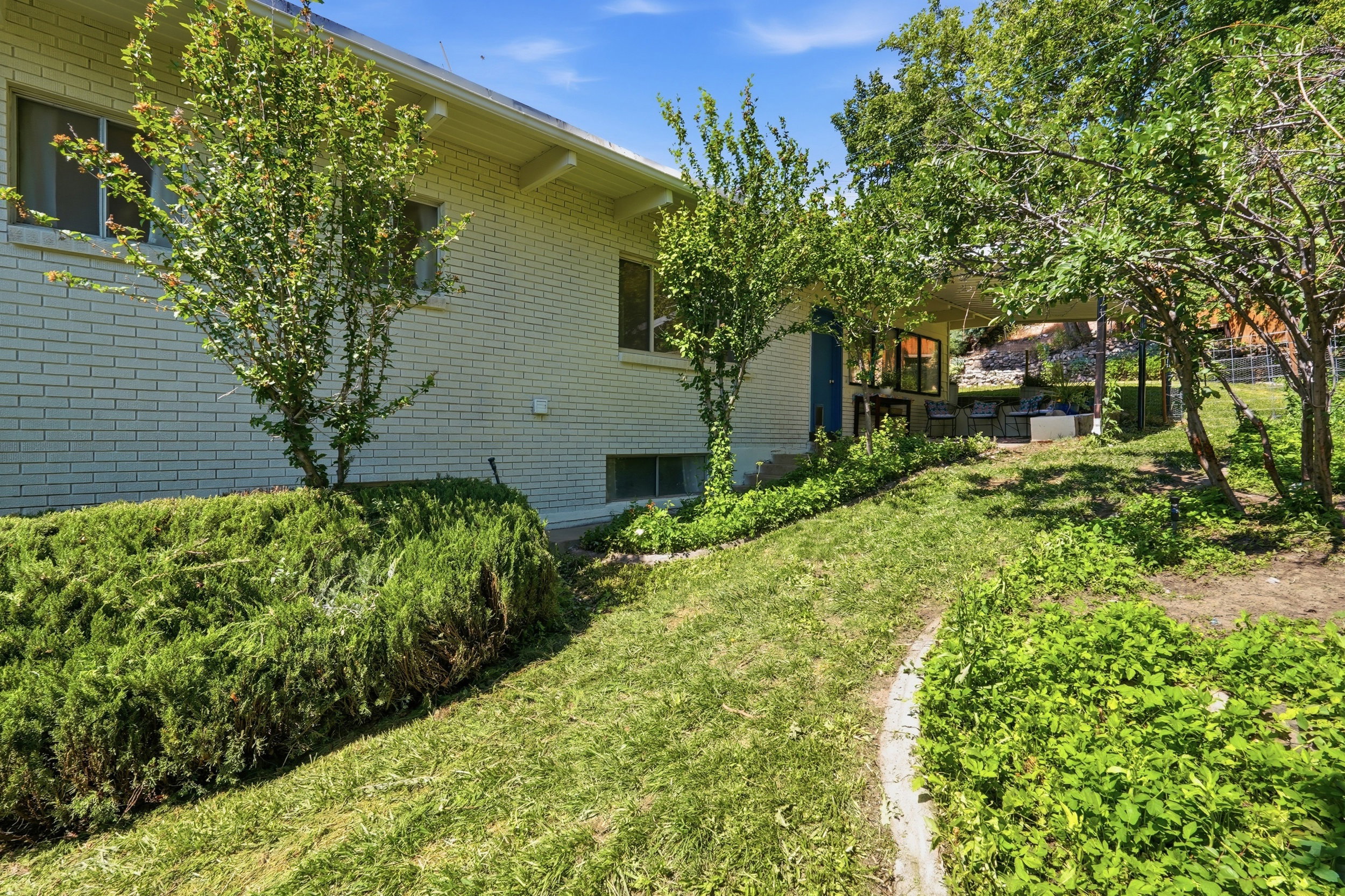 Brick exterior featuring mature landscaping and a partially covered patio area