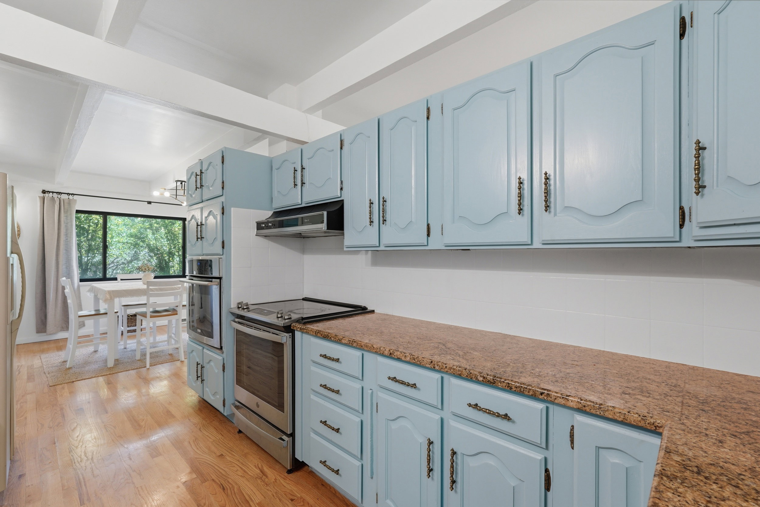 Kitchen featuring light blue cabinetry with decorative hardware, stainless steel range, built-in oven, and a built-in microwave
