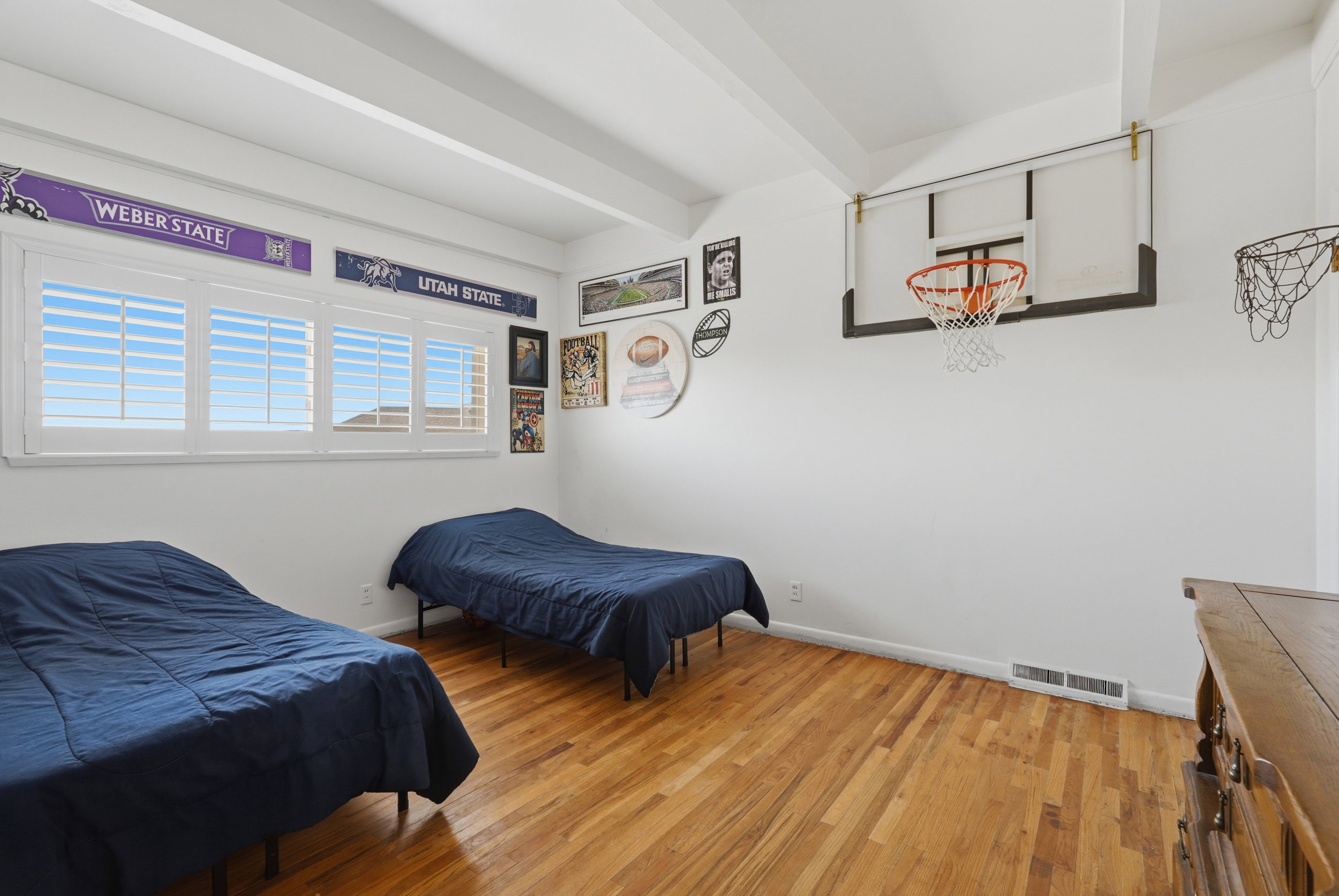 Bedroom 2 featuring wood-finish flooring, white walls, and exposed ceiling beams