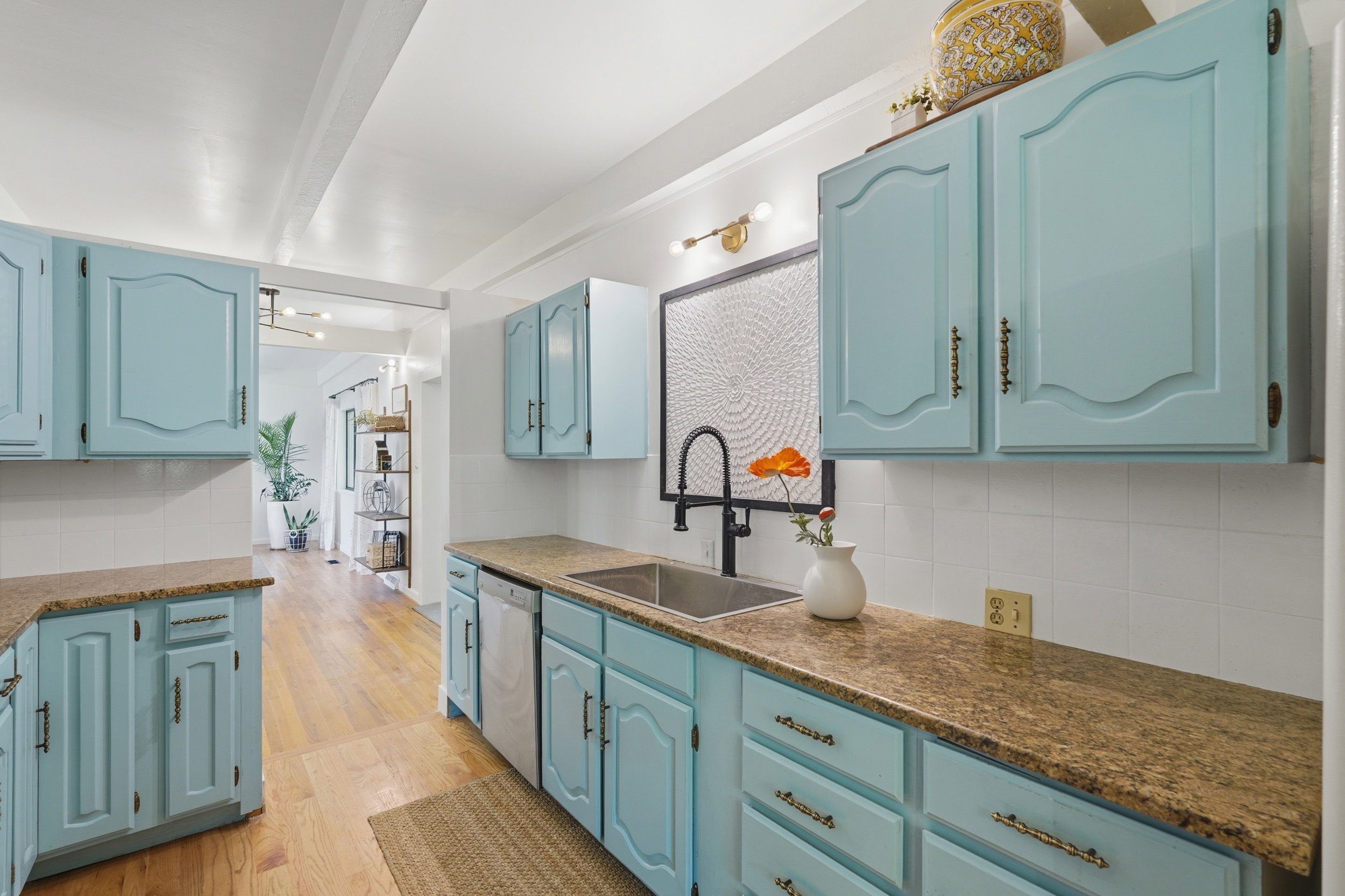 Kitchen featuring light blue cabinetry with bronze hardware, granite-style countertops, and a white subway tile backsplash
