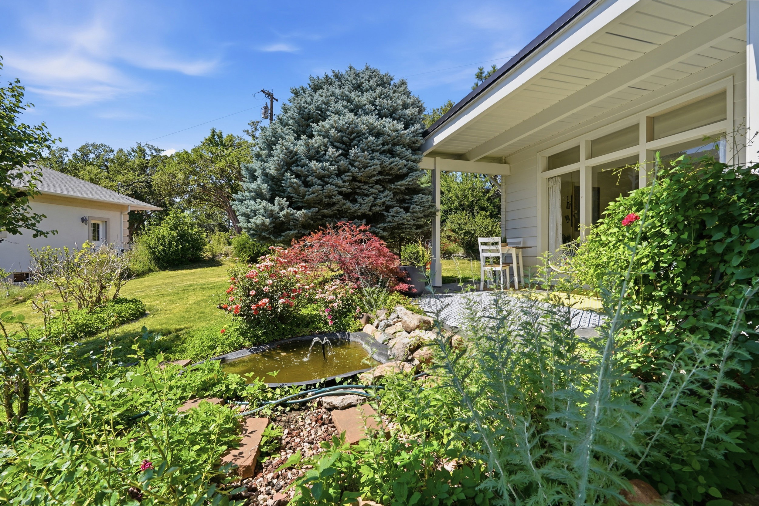 Expansive garden area featuring a water feature with fountain, mature trees, and lush landscaping