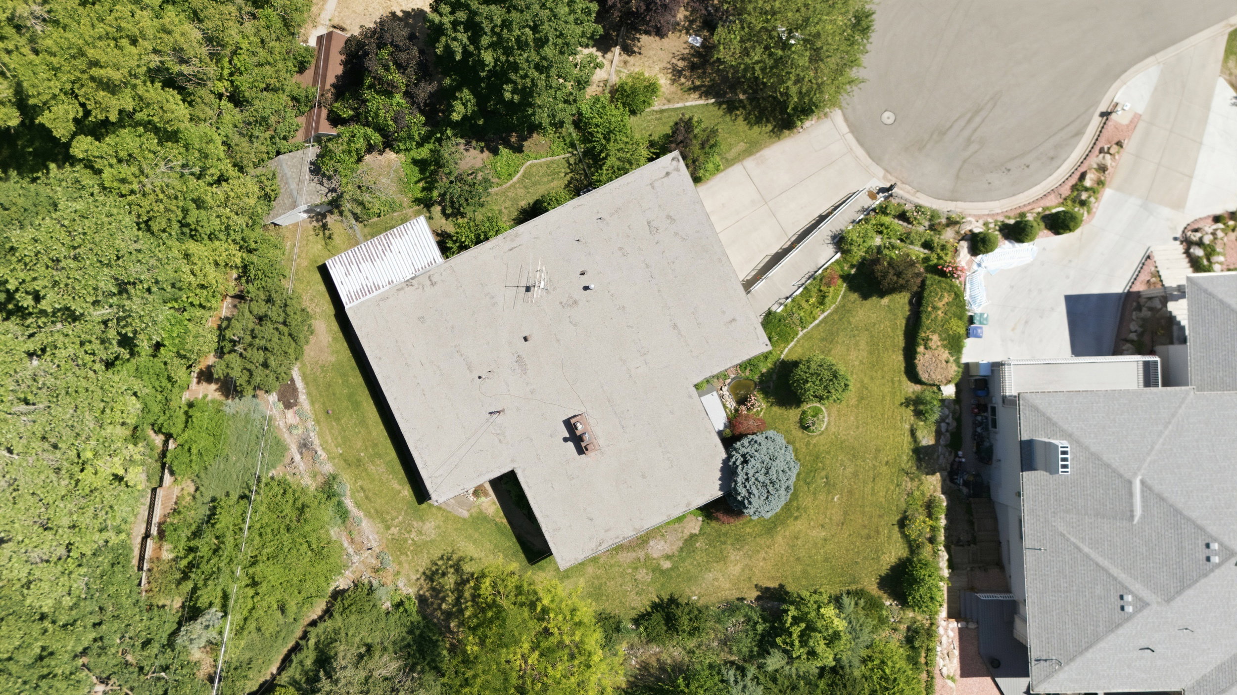 Aerial perspective showcasing the property's expansive lot, mature landscaping, and curved driveway