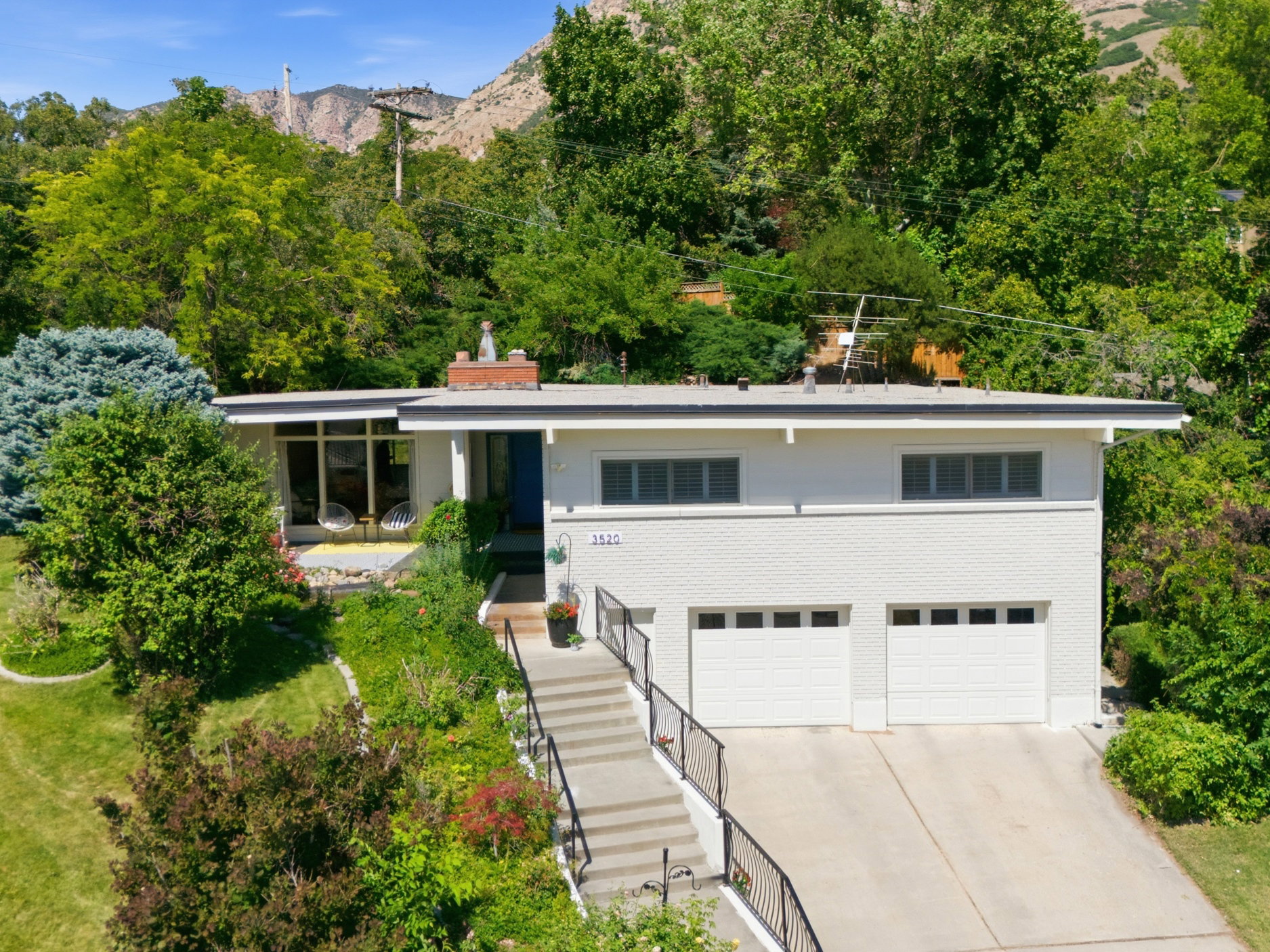 Mid-century modern residence featuring a white brick facade, flat roofline, and a two-car garage