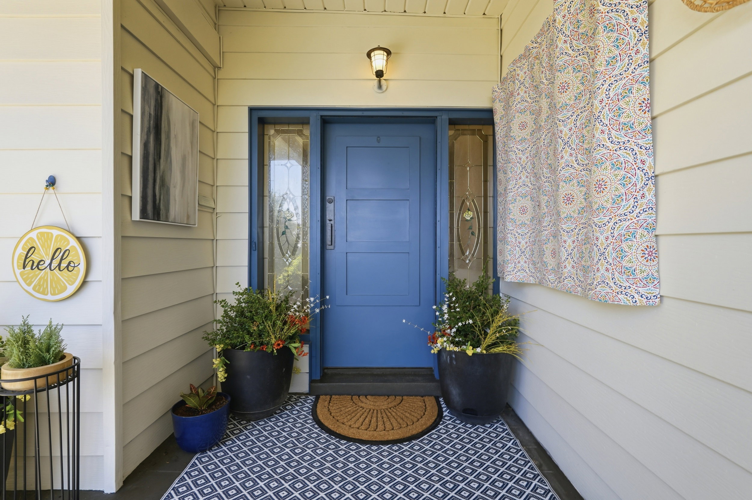 Entryway featuring a blue paneled door with decorative sidelight windows, overhead lighting fixture, and horizontal siding
