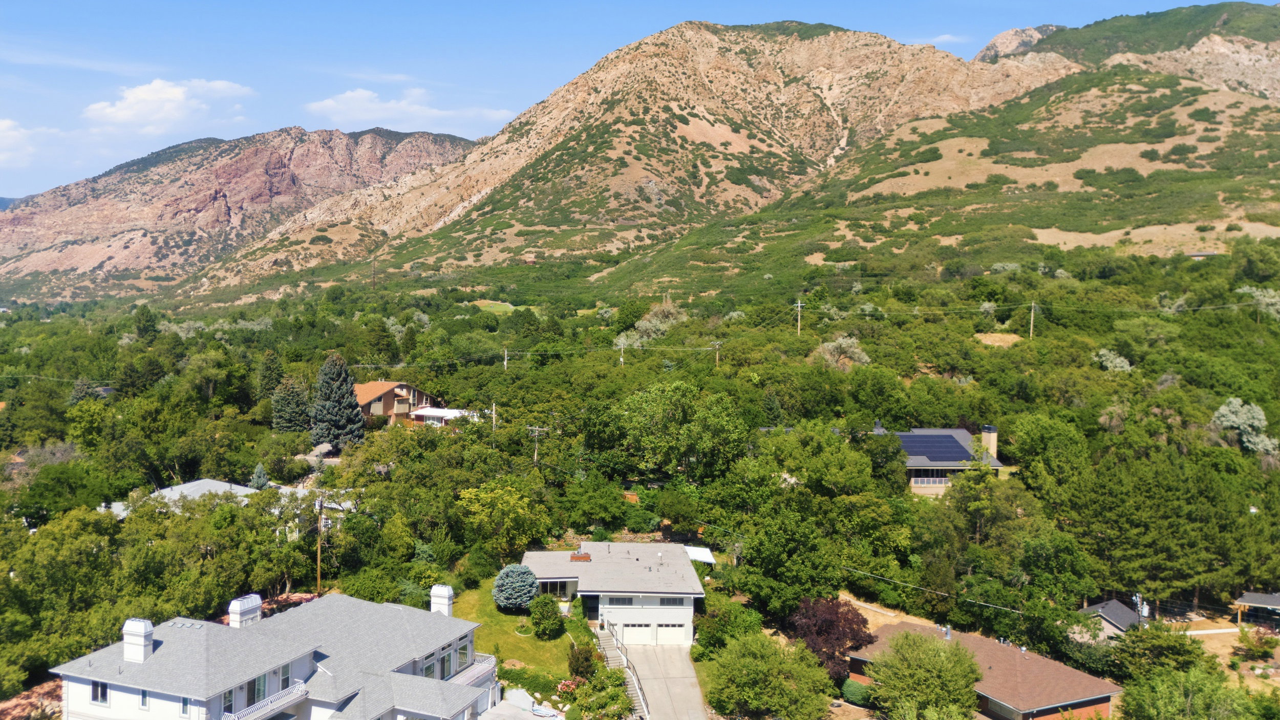 Aerial perspective showcasing a property nestled within a lush, green landscape, framed by expansive mountains