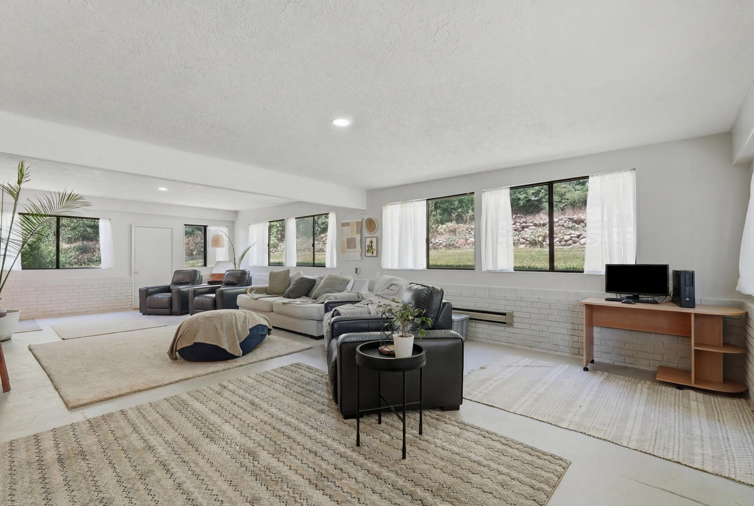 Spacious open-concept room featuring light-toned walls and multiple windows providing natural illumination