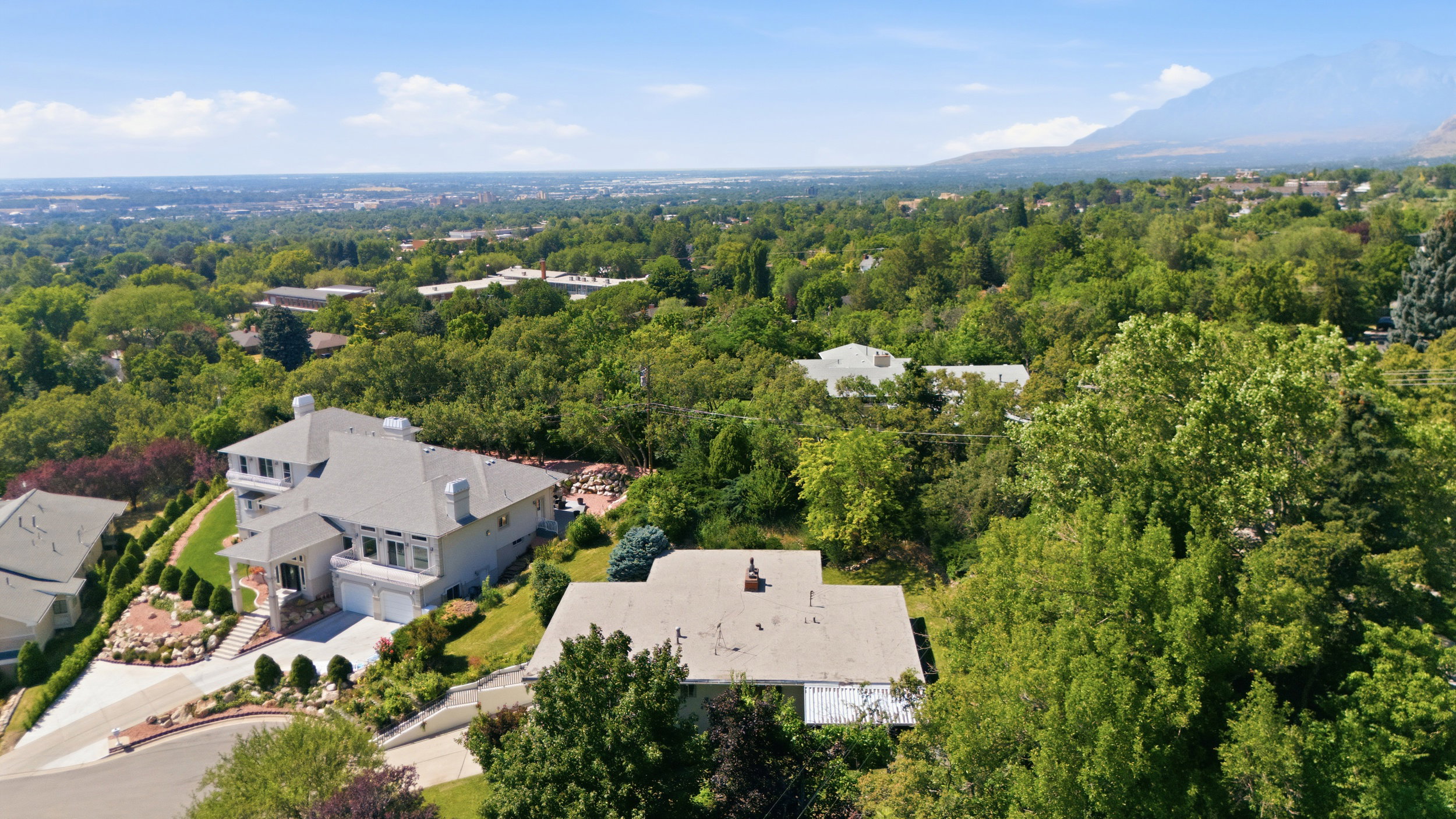 Expansive property featuring a multi-level residence with a light-colored exterior and a prominent gabled roofline
