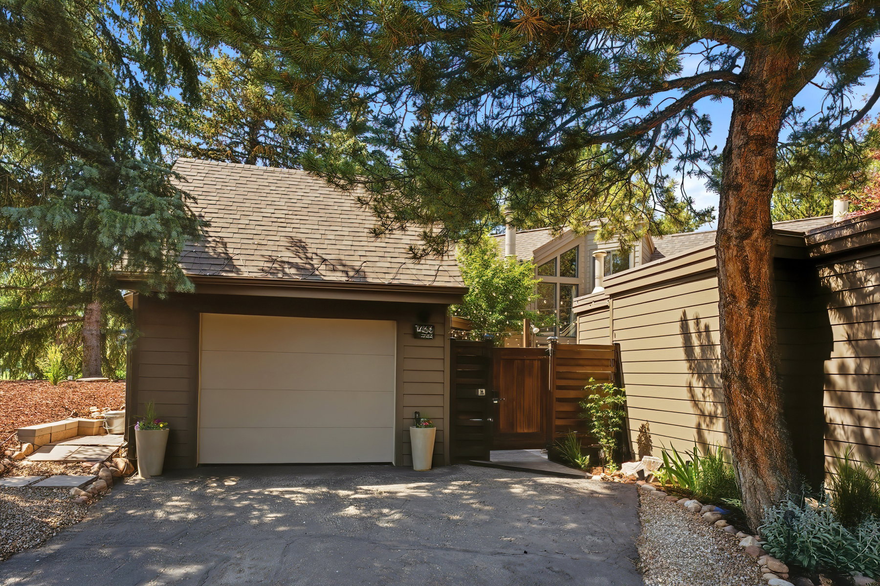 Attached garage with a tan overhead door, flanked by a privacy fence and a paved driveway