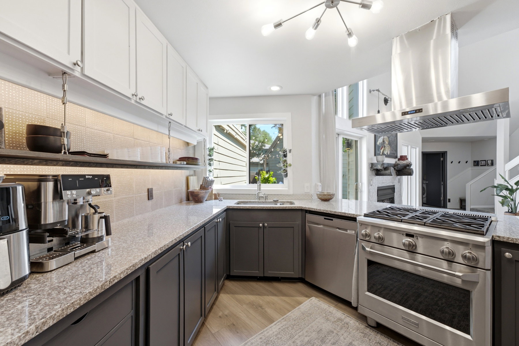 Modern kitchen featuring white upper cabinetry and grey lower cabinetry, granite countertops, a stainless steel range with matching ventilation hood, and wood-finish flooring