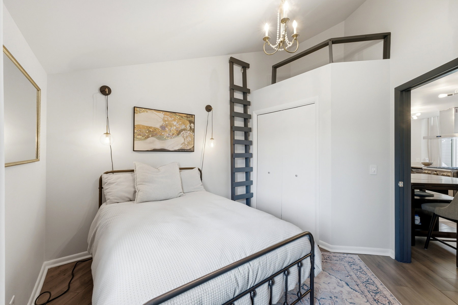 Loft bedroom featuring sloped ceilings, wood-finish flooring, and a built-in ladder providing access to an upper-level space