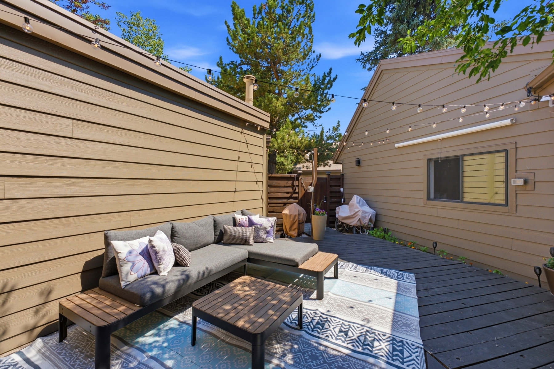 Private outdoor patio featuring dark wood-finish decking and string lighting