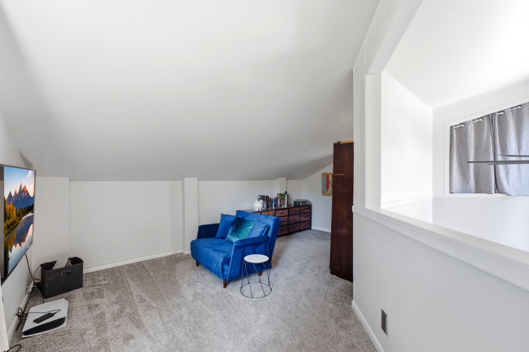 Carpeted bonus room featuring sloped ceilings, white walls, and a built-in half-wall partition